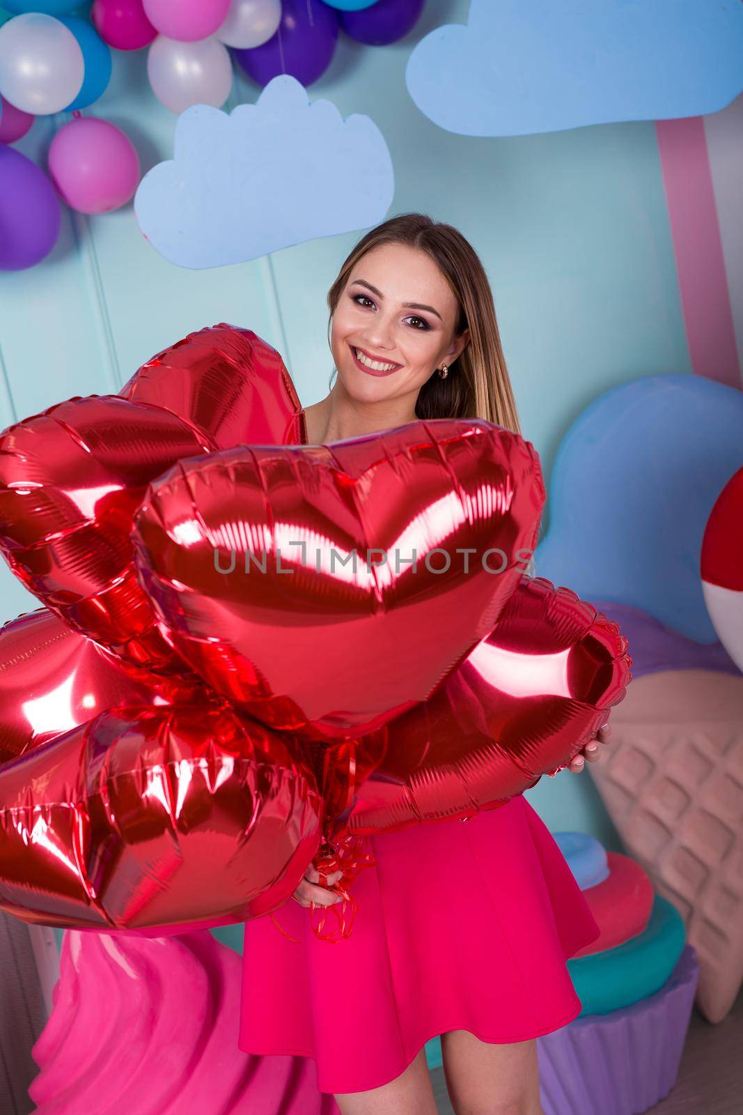 Fashion portrait of young woman in pink dress with an air balloons, candy on a colorful background by StudioPeace
