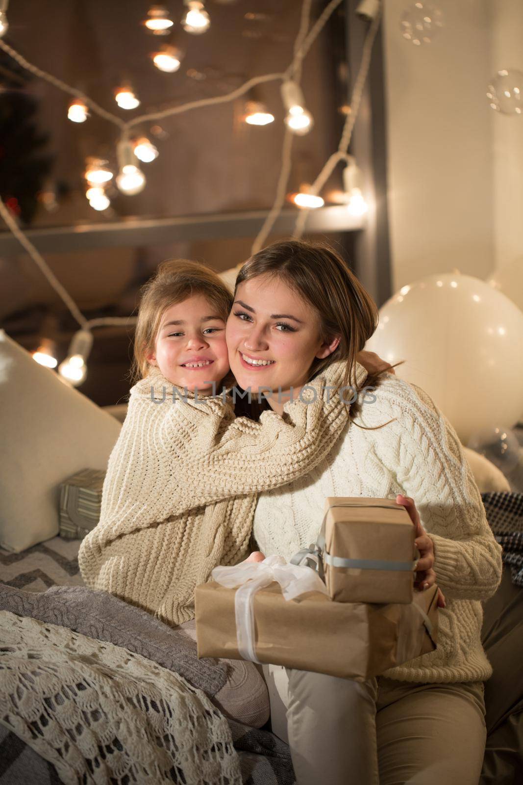 Beautiful mother and daughter opening a magical Christmas gift in the cozy interior of the house. New year