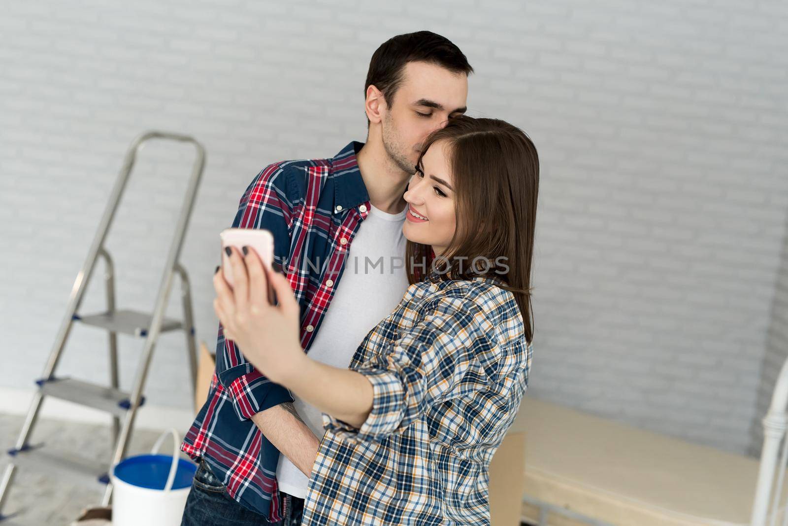 Young couple makes selfie while moving to a new apartment. Moving newlyweds to new housing by StudioPeace