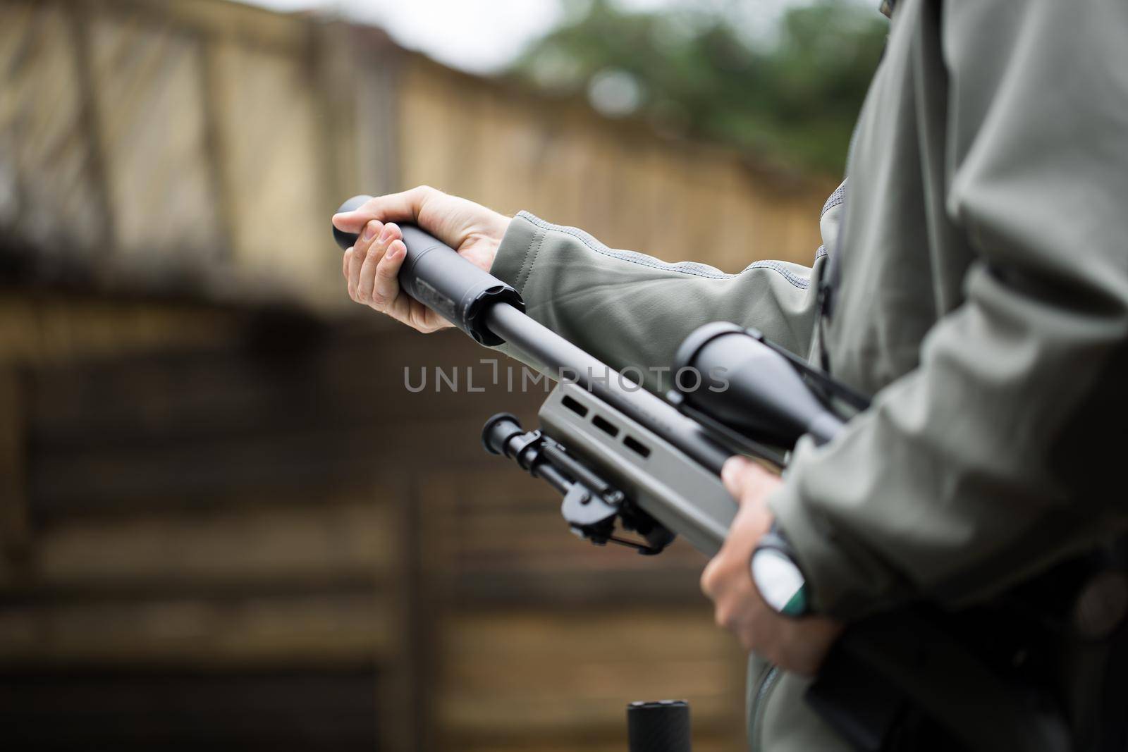 Military holds a pistol with a silencer.