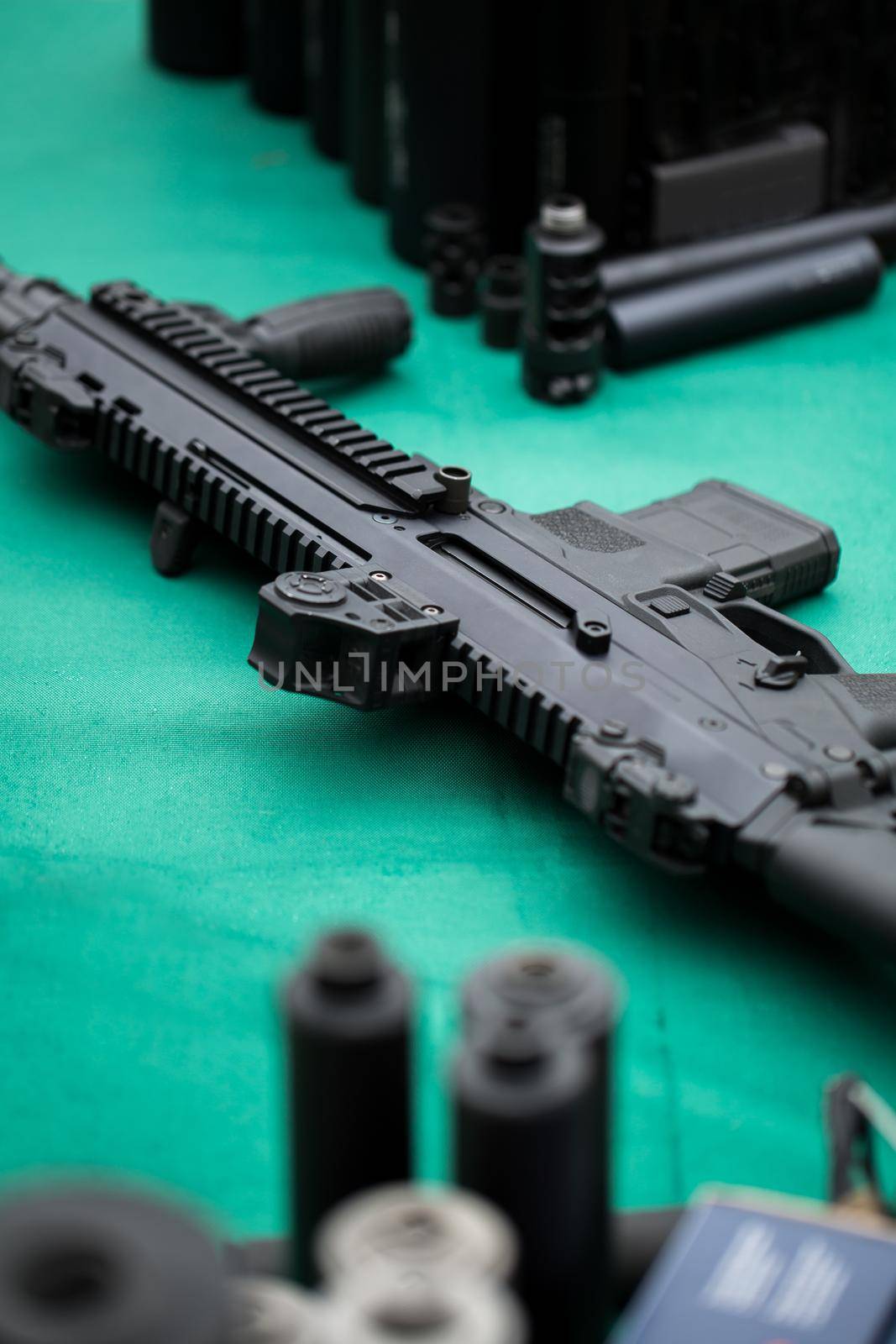 An assault rifle with a silencer on a green table. by StudioPeace