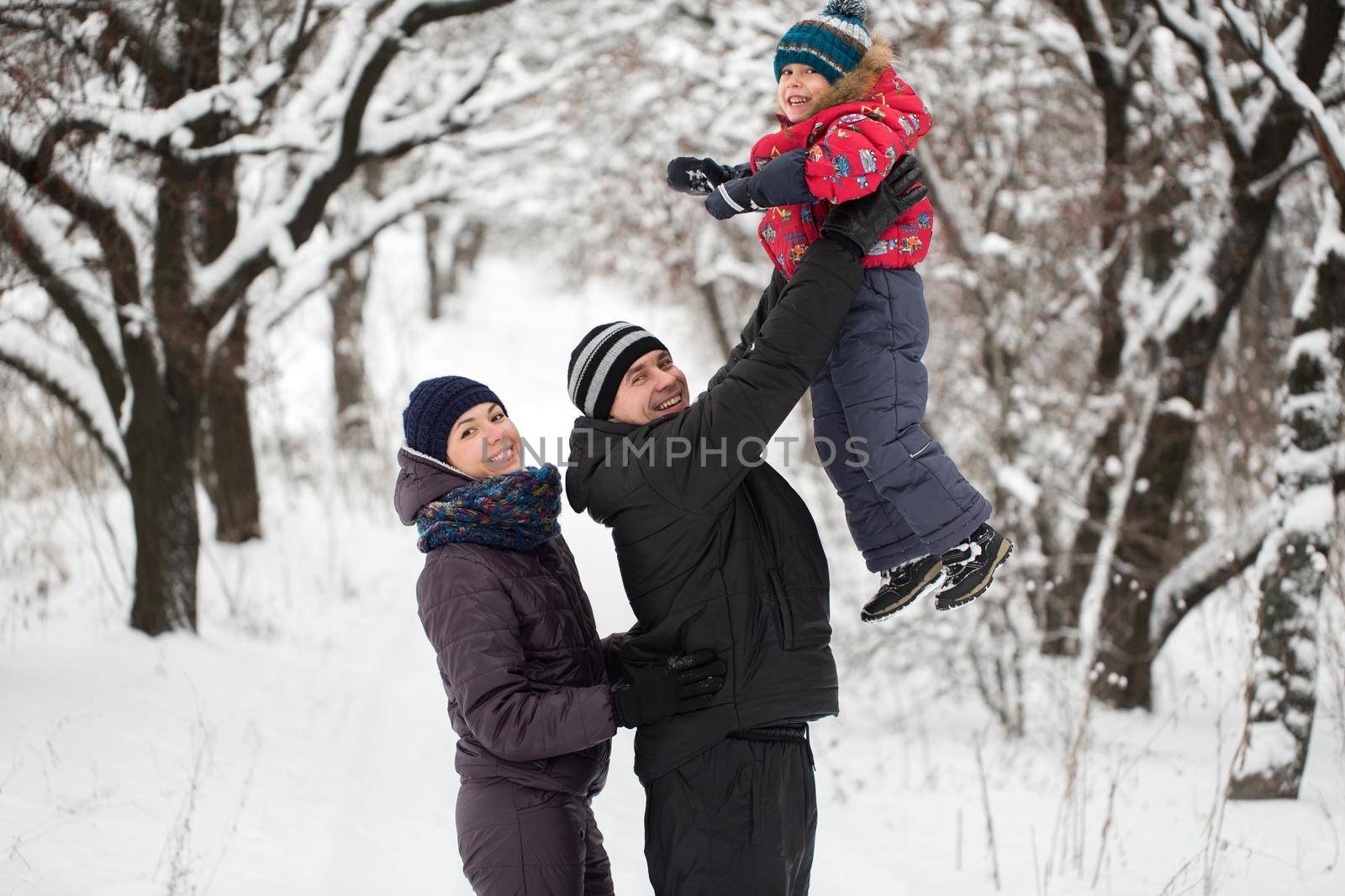 A young family with a child walking through a snow-covered forest