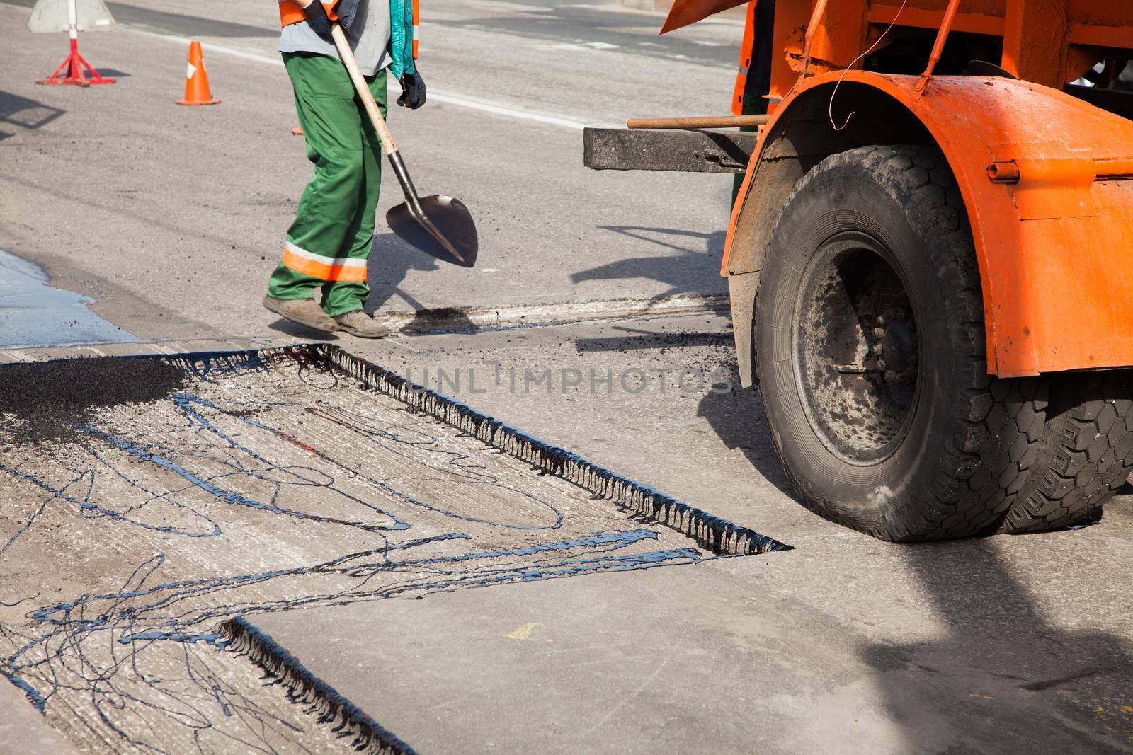 Workers on Asphalting paver machine during Road street repairing works. Street resurfacing. Fresh asphalt construction. Bad road. by StudioPeace