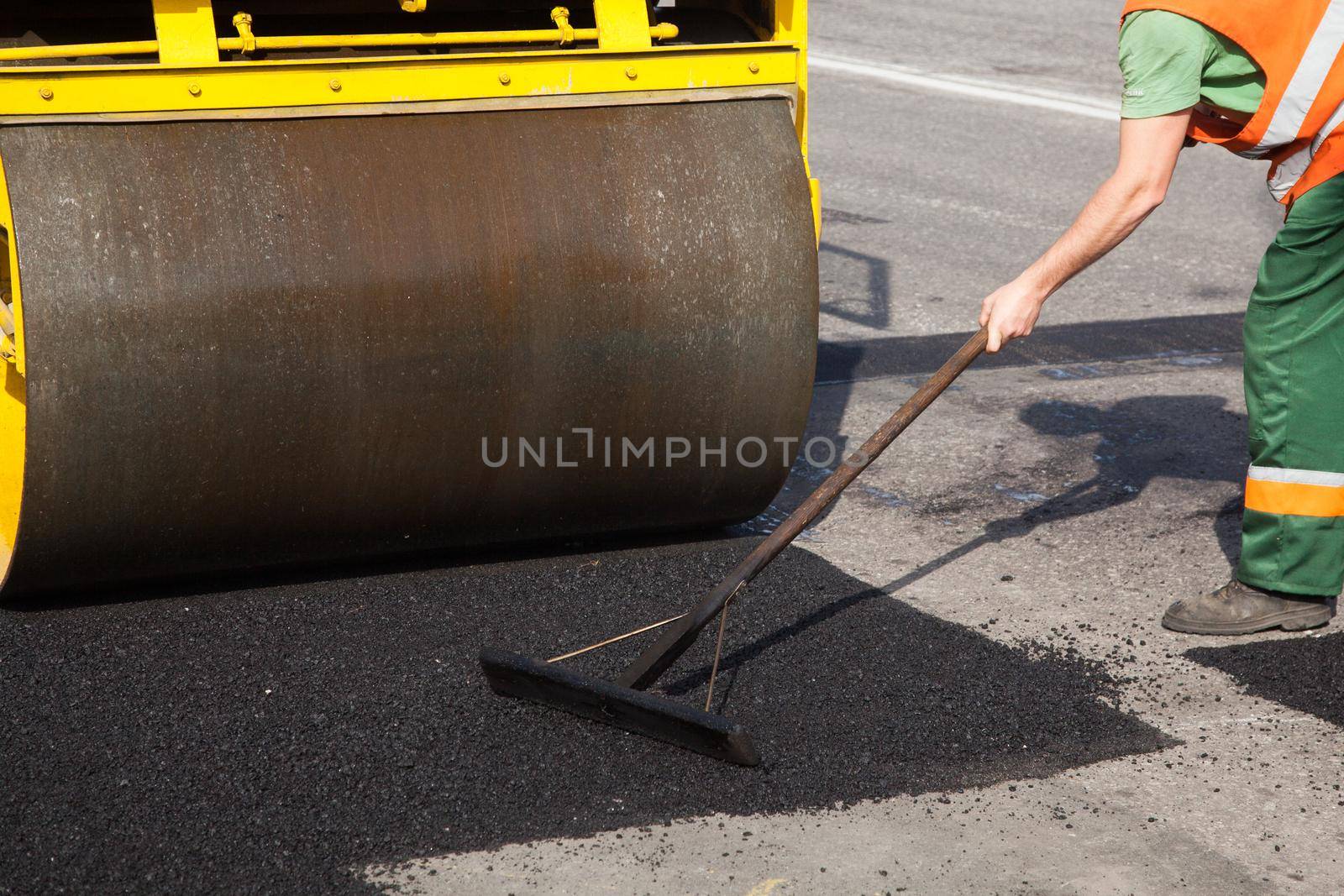 Pavement machine laying fresh asphalt or bitumen on top of the gravel base during highway construction