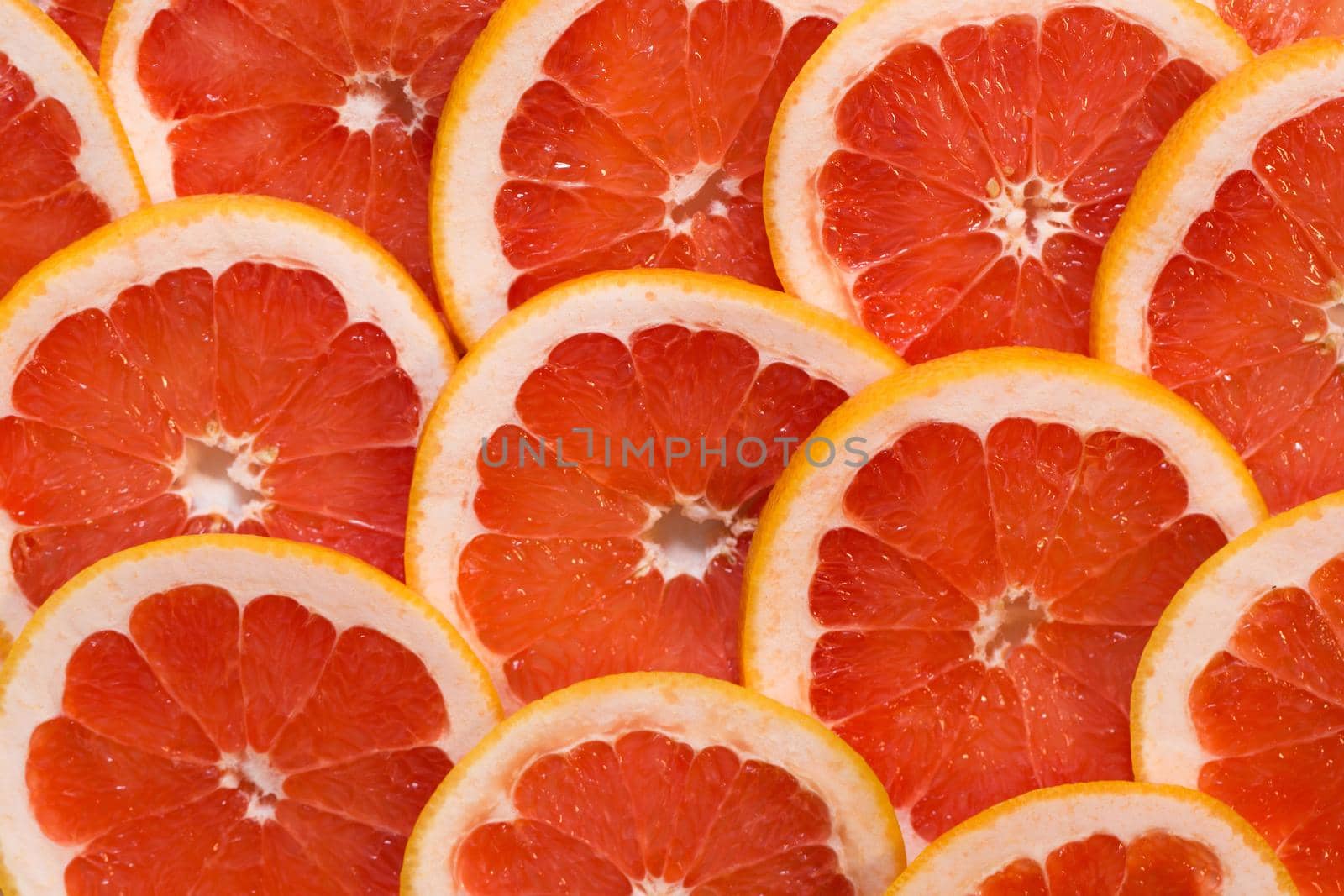 Bright red background with juicy slices of grapefruit. Healthy food background by StudioPeace