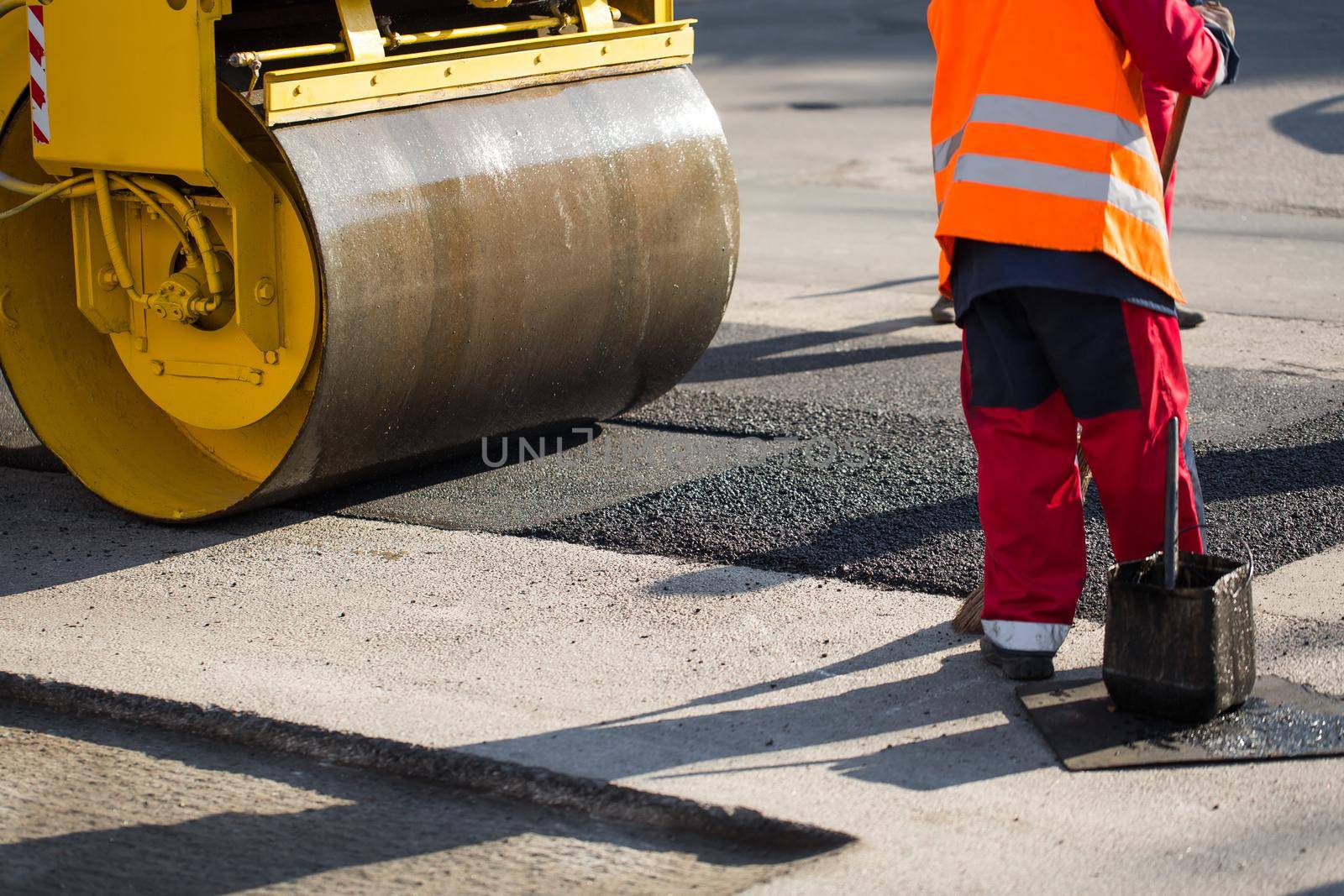 Road repairs. A road roller compacting asphalt. by StudioPeace