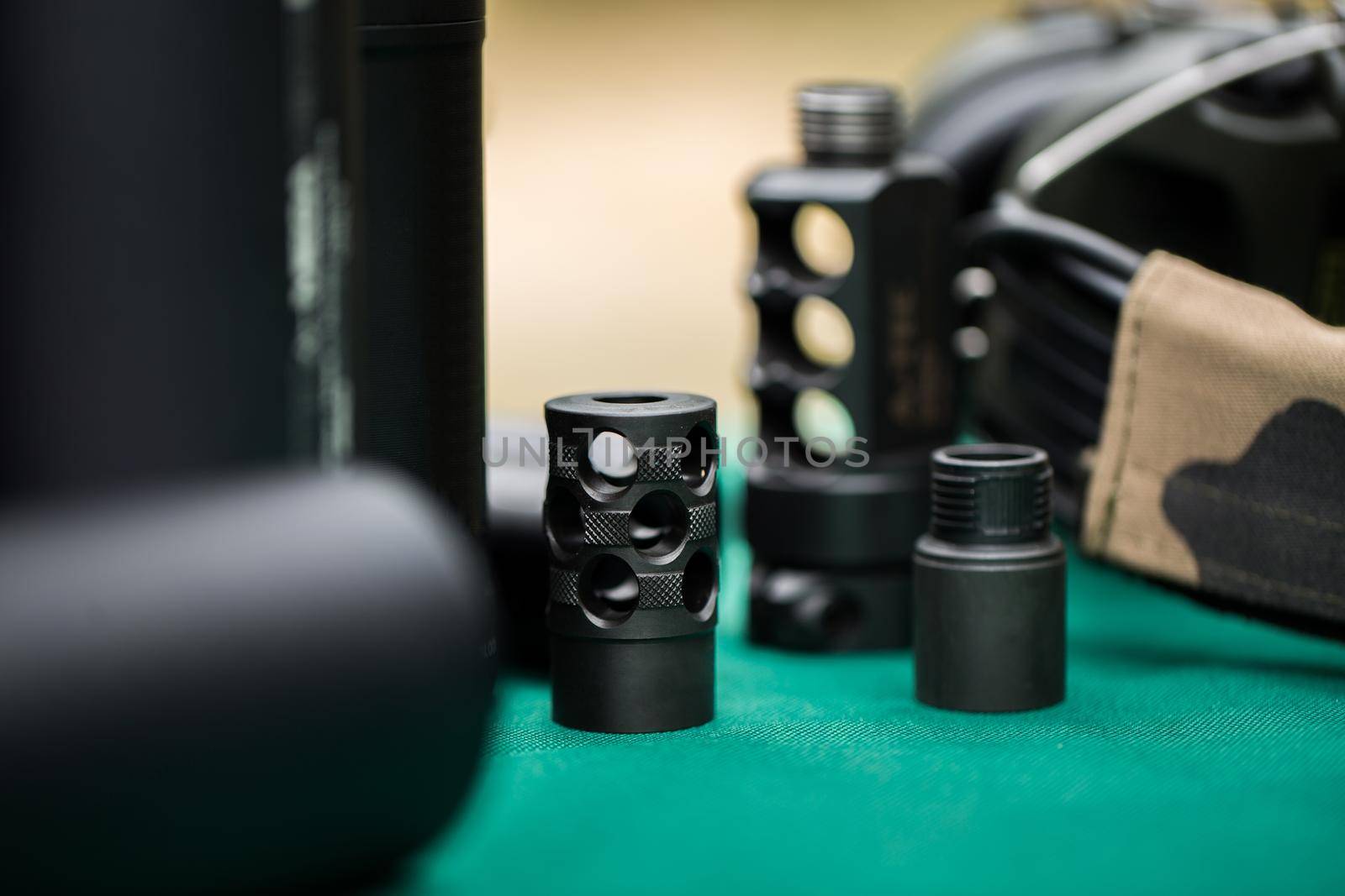 silencers for weapons are on the green table. by StudioPeace