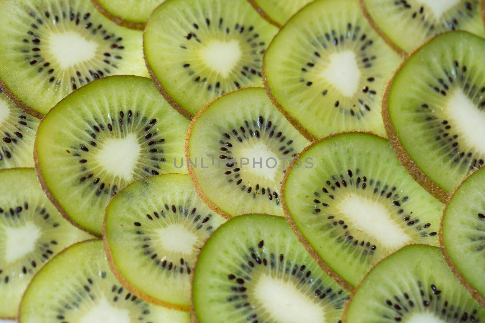 Bright green background with slices of juicy kiwi. Healthy food background.