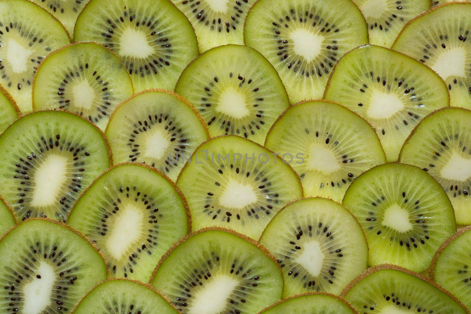 Bright green background with slices of juicy kiwi. Healthy food background.