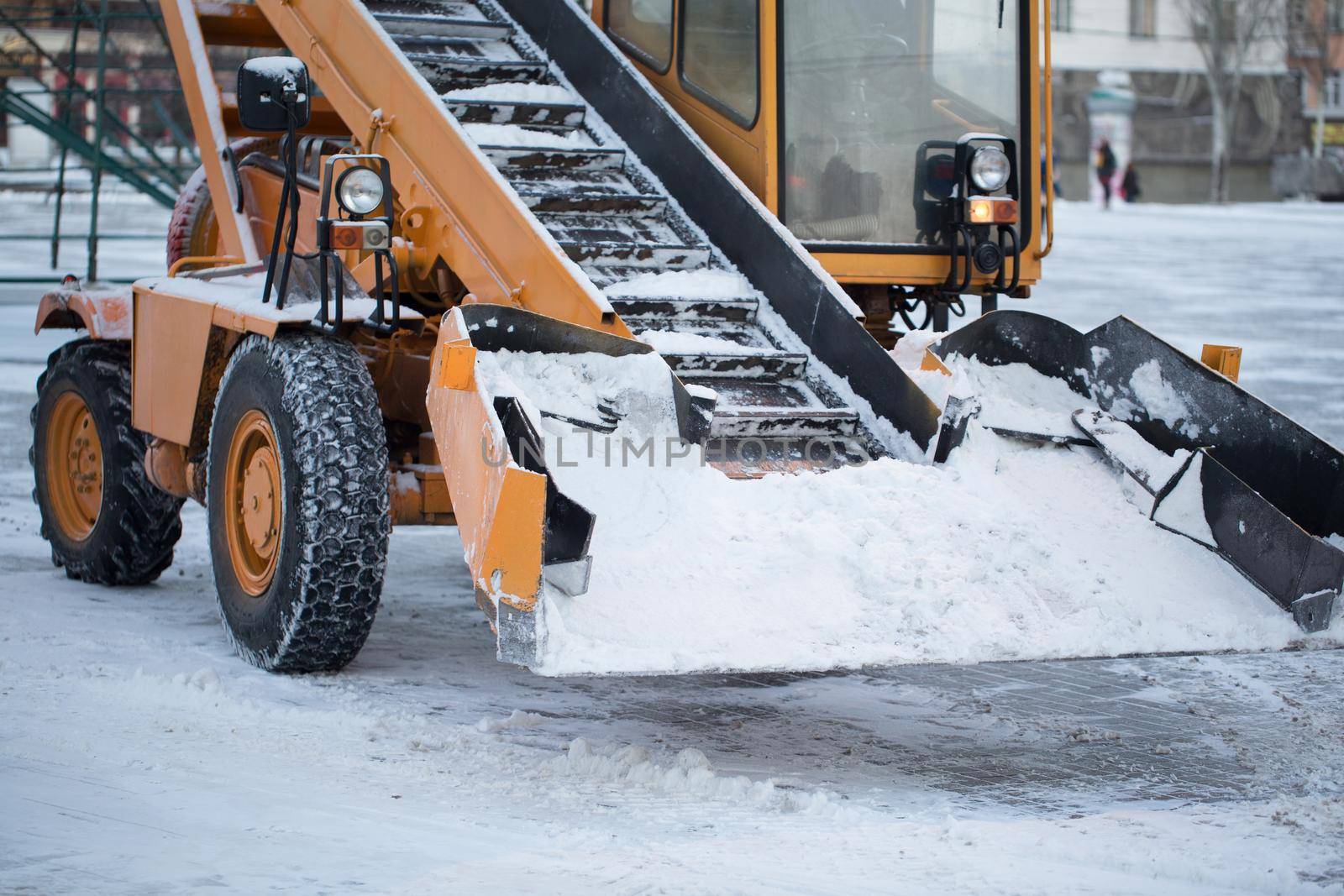 Tractor cleaning the road from the snow. Excavator cleans the streets of large amounts of snow in city.