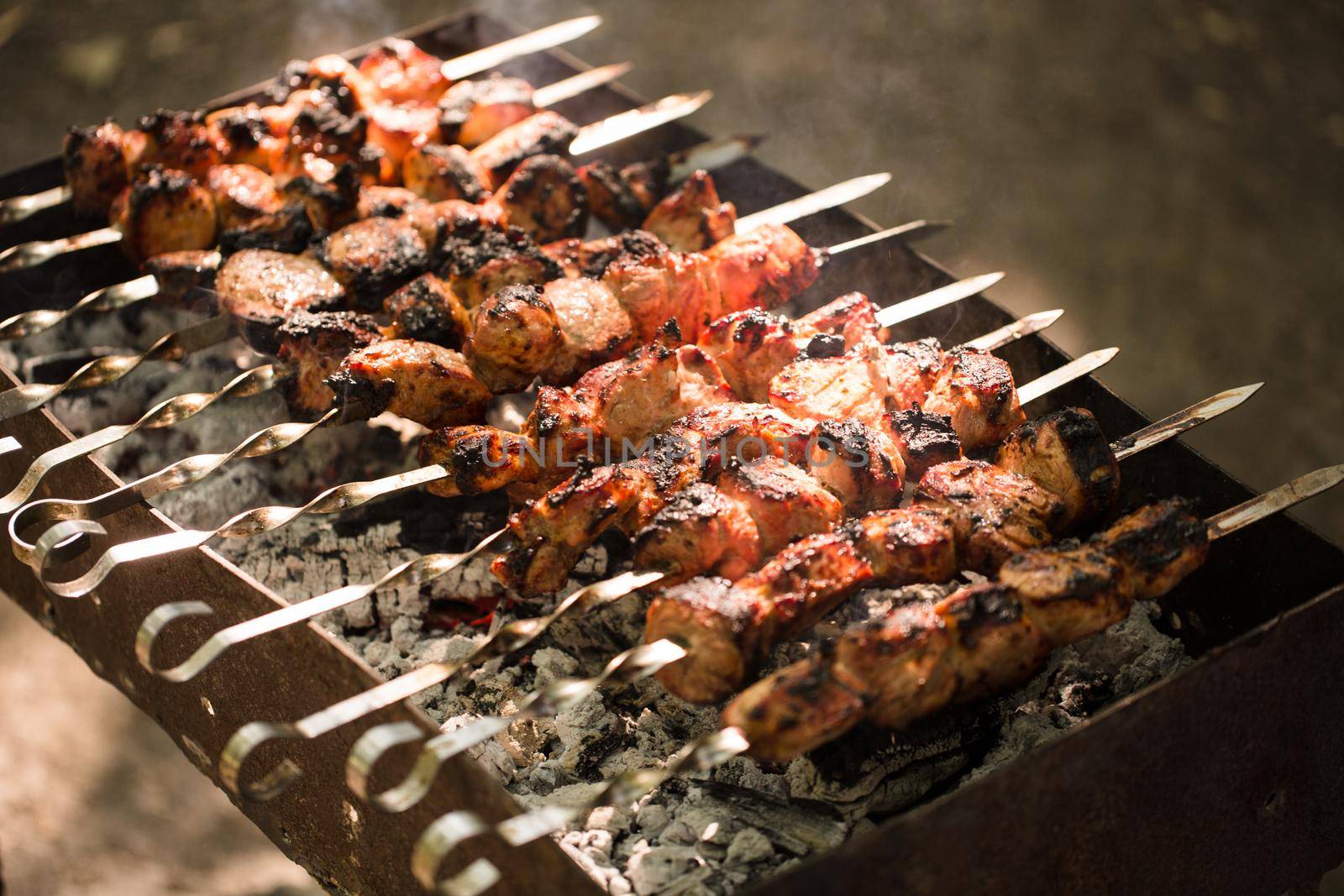 Marinated shashlik preparing on a barbecue grill over charcoal. Shashlik or Shish kebab popular in Eastern Europe. Shashlyk skewered meat was originally made of lamb. Roast Beef Kebabs On BBQ Grill.