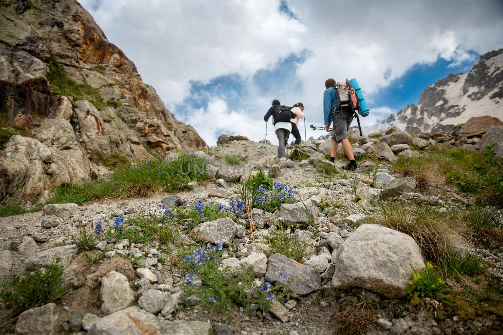 People with backpacks and scandinavian sticks climb the mountains in Caucasus