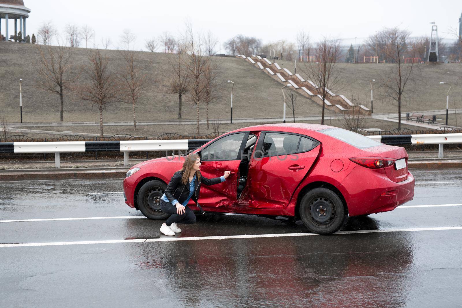 Woman sits near a broken car after an accident. call for help. car insurance