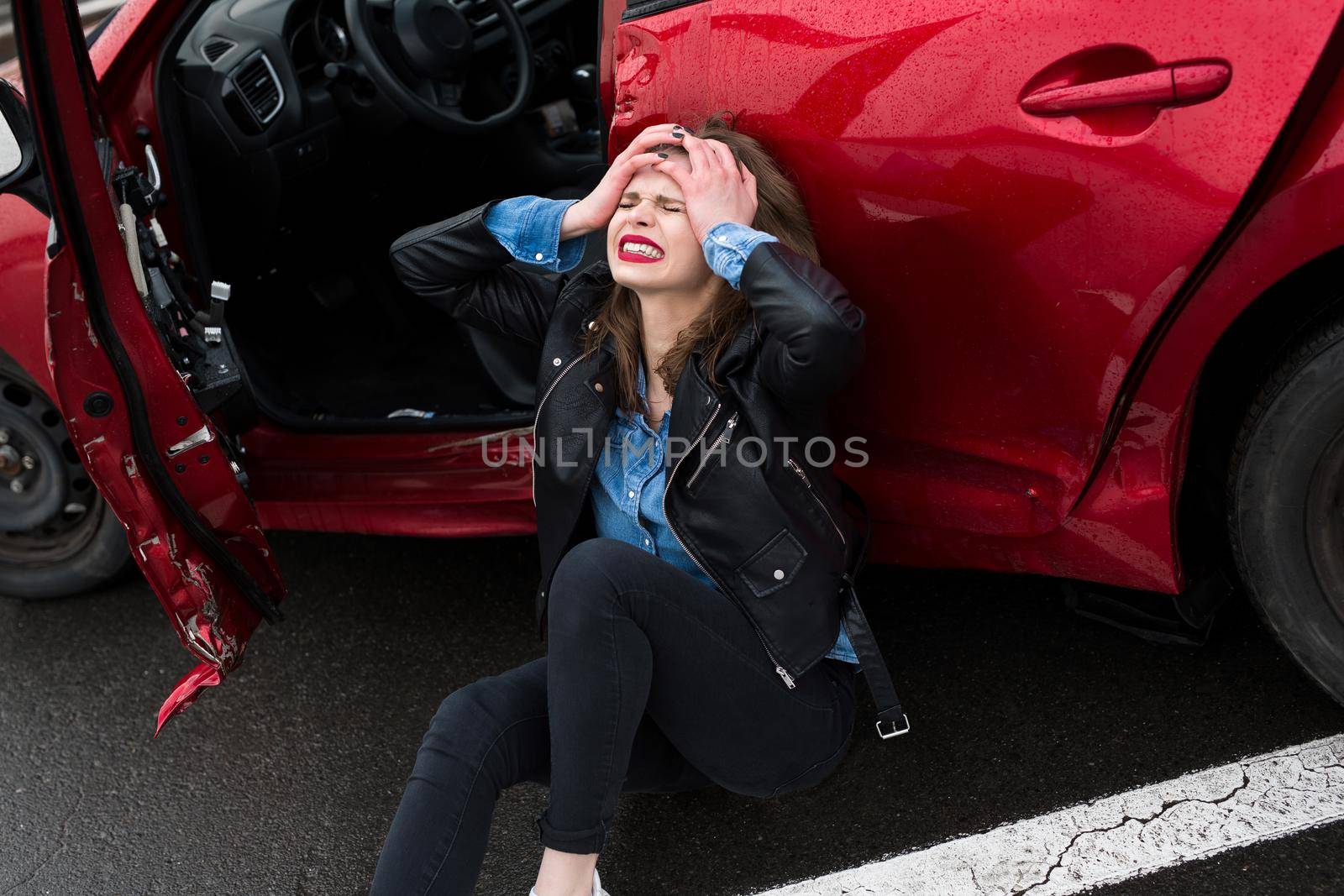 Woman sitting on the road after an accident. Injured woman feeling bad after having a car crash. by StudioPeace