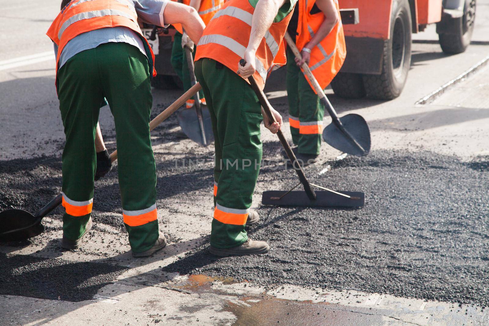 Workers on Asphalting paver machine during Road street repairing works. Street resurfacing. Fresh asphalt construction. Bad road