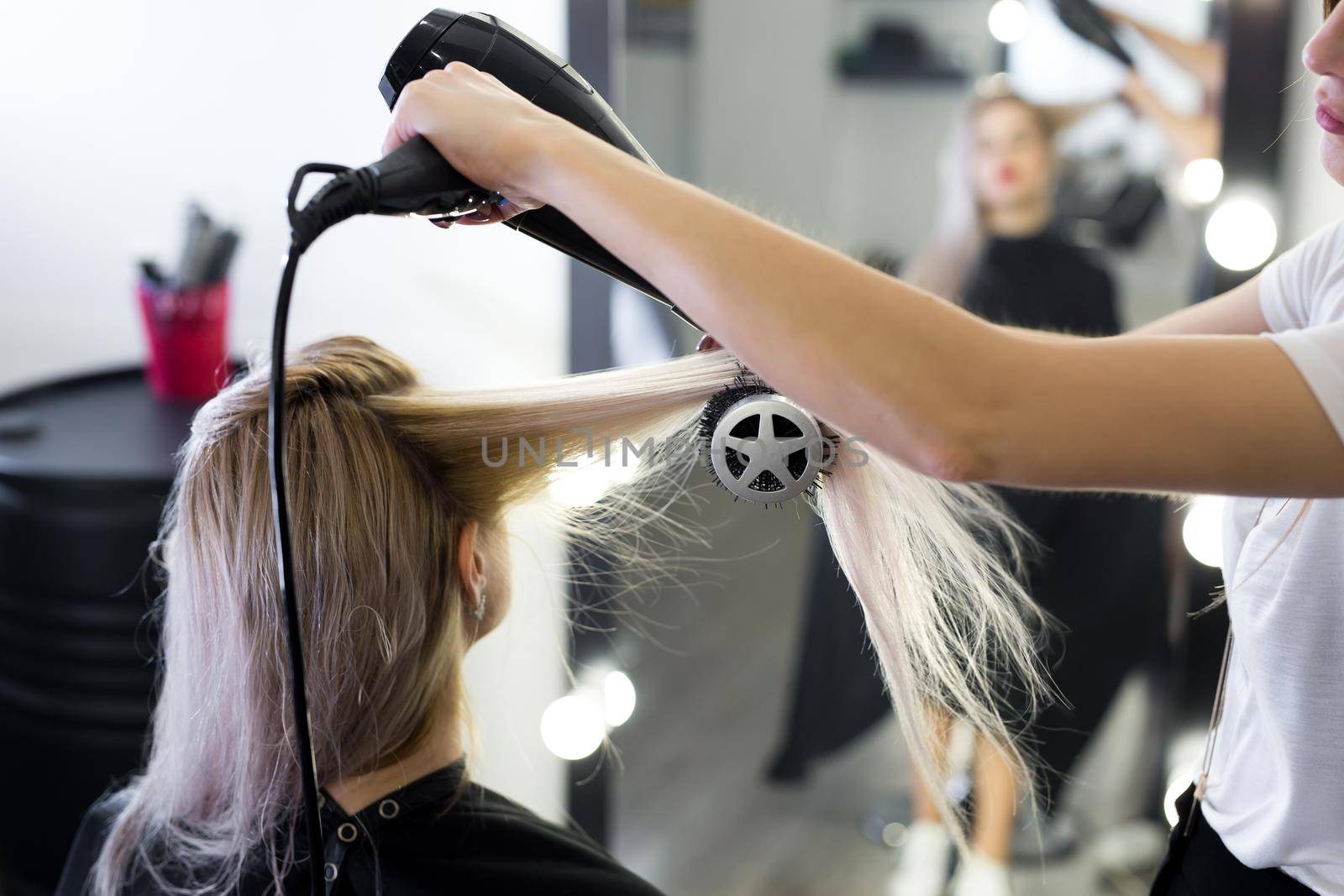Drying long blonde hair with hair dryer and round brush. by StudioPeace