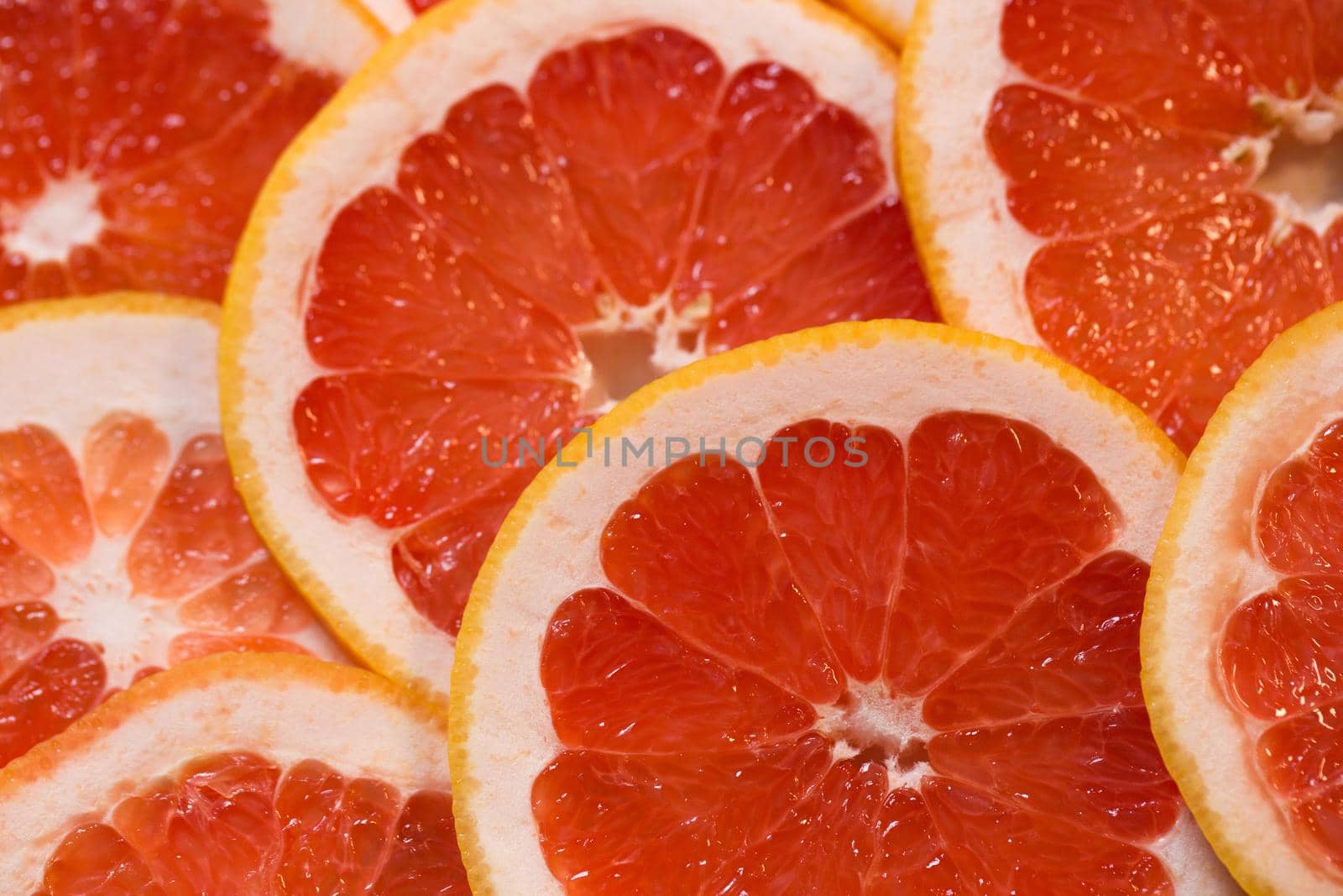 Bright red background with juicy slices of grapefruit. Healthy food background.