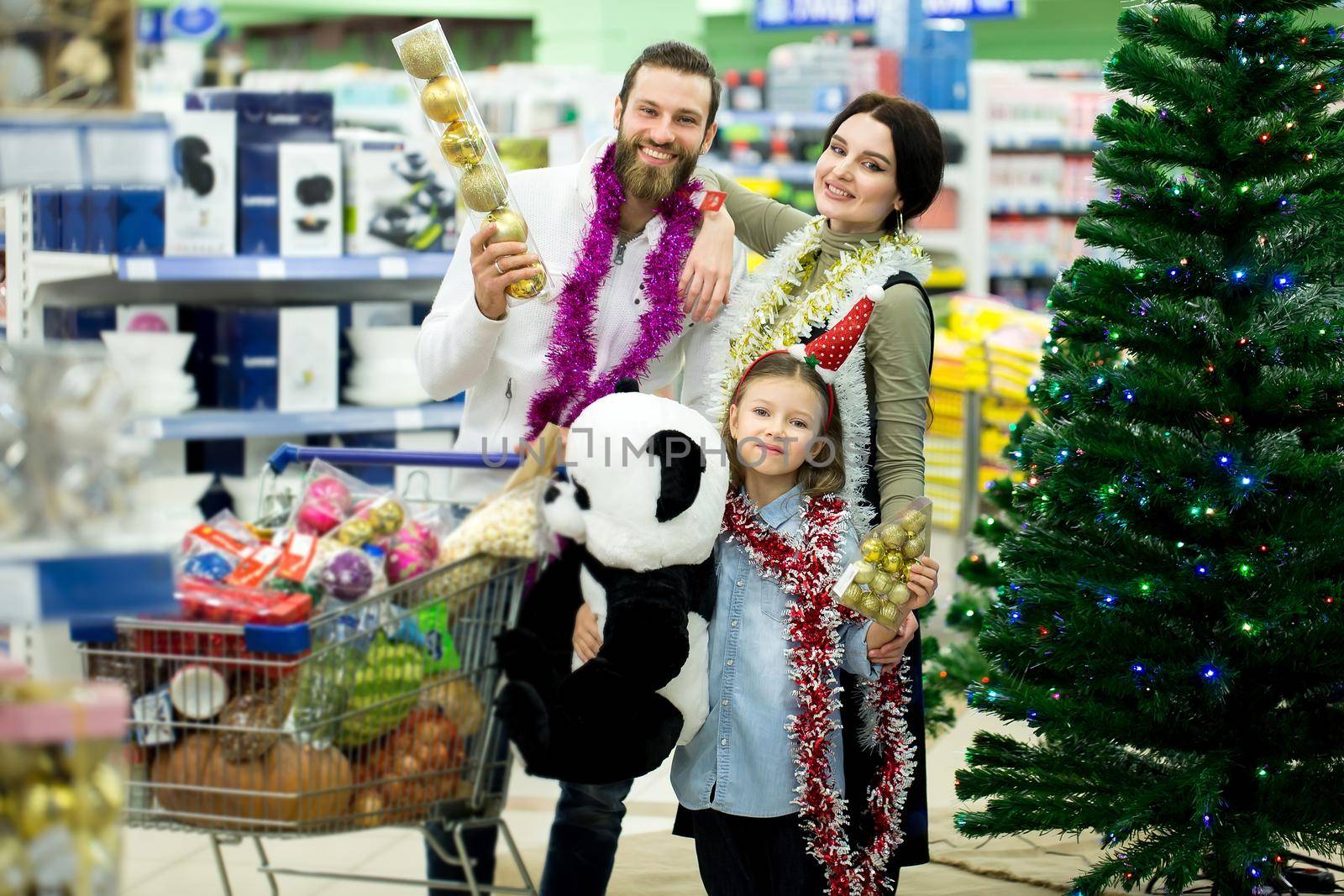 Happy young family in the supermarket chooses gifts for the new year. by StudioPeace