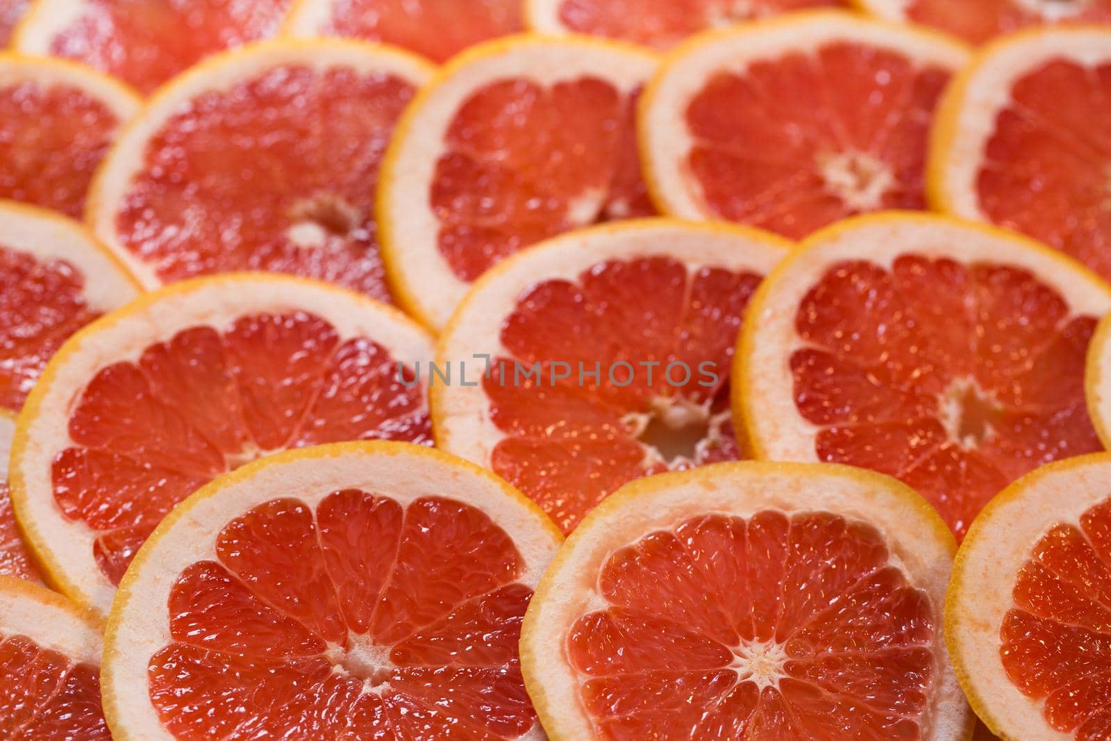 Bright red background with juicy slices of grapefruit. Healthy food background by StudioPeace