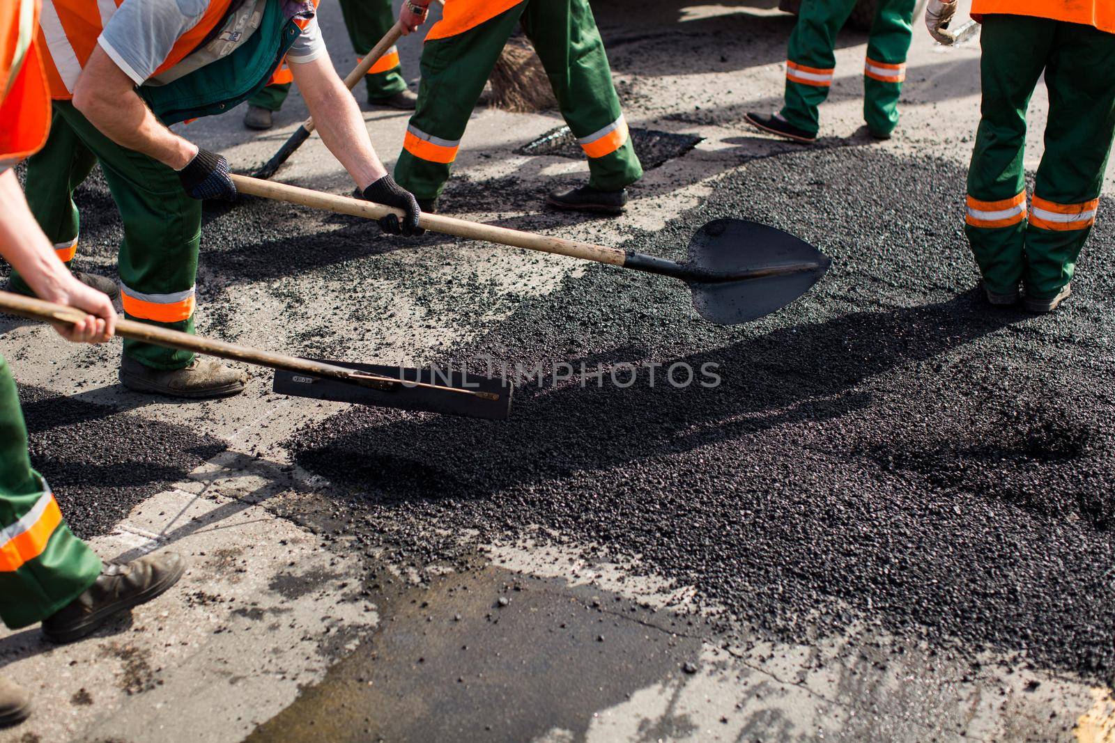 Workers on Asphalting paver machine during Road street repairing works. Street resurfacing. Fresh asphalt construction. Bad road. by StudioPeace