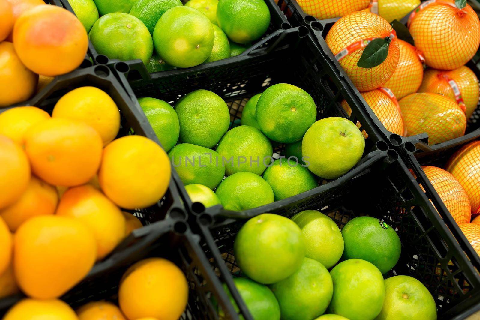 Fresh citrus are on the shelf in the store. a variety of citrus fruits. oranges, tangerines, lime, lemons. supermarket. by StudioPeace