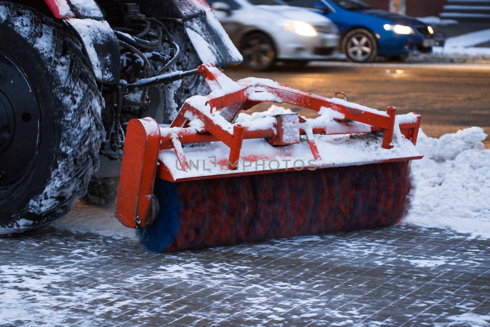 Tractor brushes snow on the road in the evening. by StudioPeace