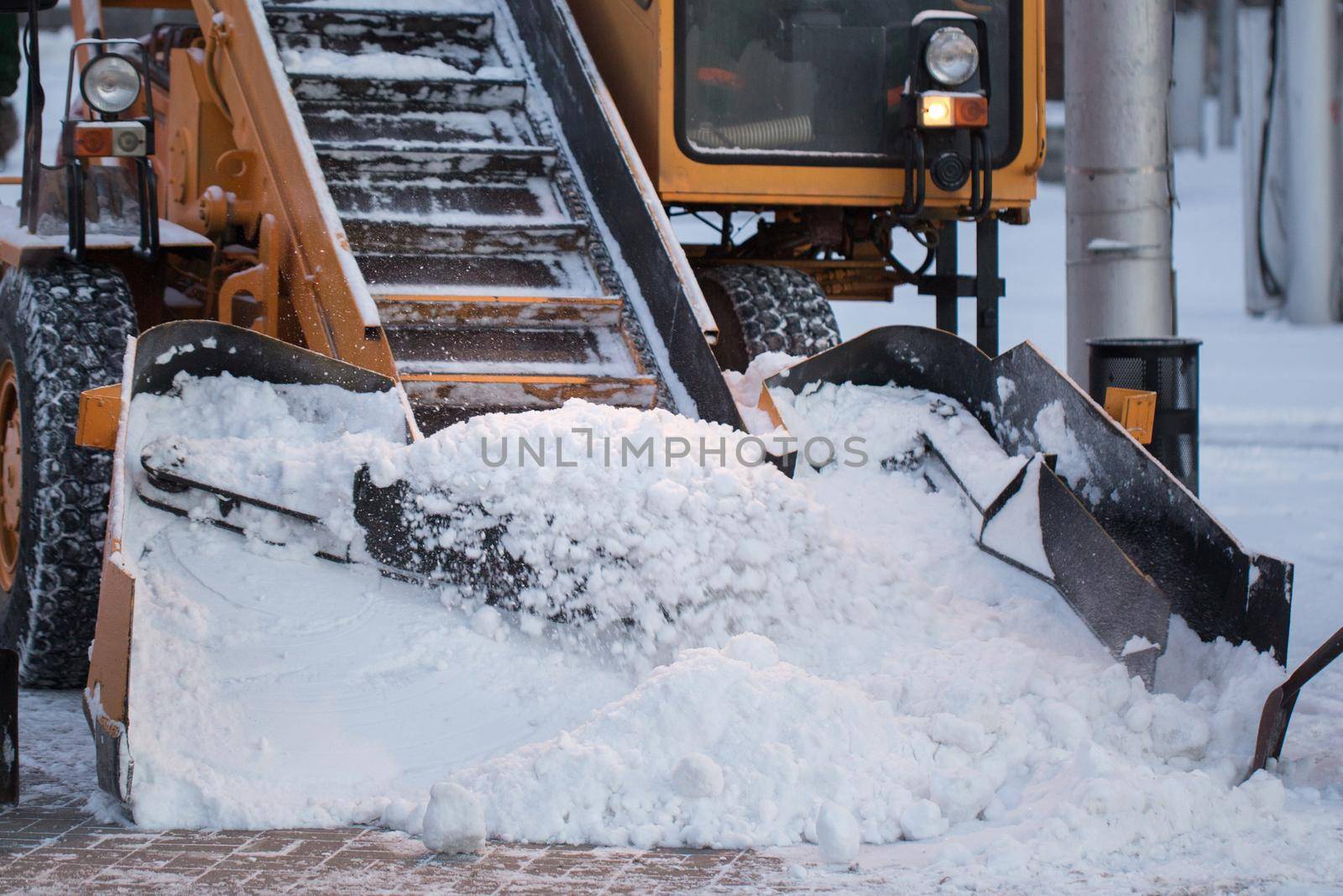 Tractor cleaning the road from the snow. Excavator cleans the streets of large amounts of snow in city.