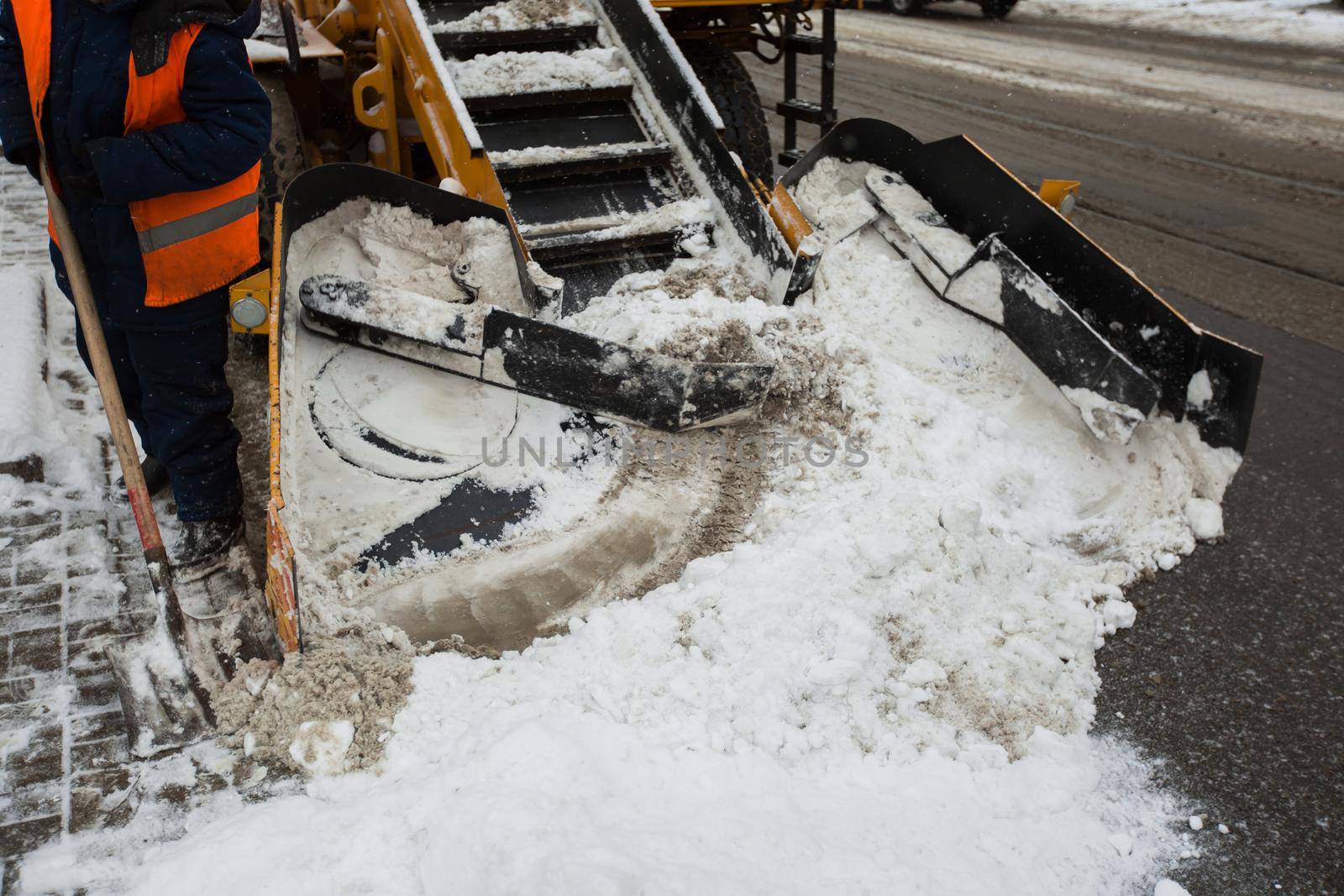 Snow-removal machine cleans the street of snow. Workers sweep snow from road in winter, Cleaning road from snow storm.