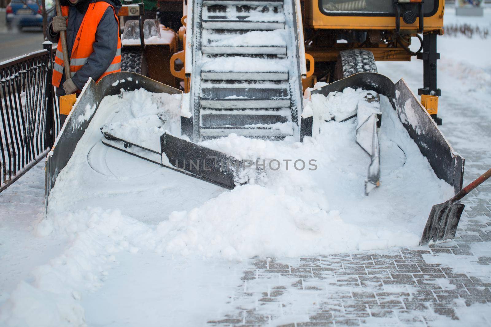 Tractor cleaning the road from the snow. Excavator cleans the streets of large amounts of snow in city. Workers sweep snow from road in winter, Cleaning road from snow storm by StudioPeace
