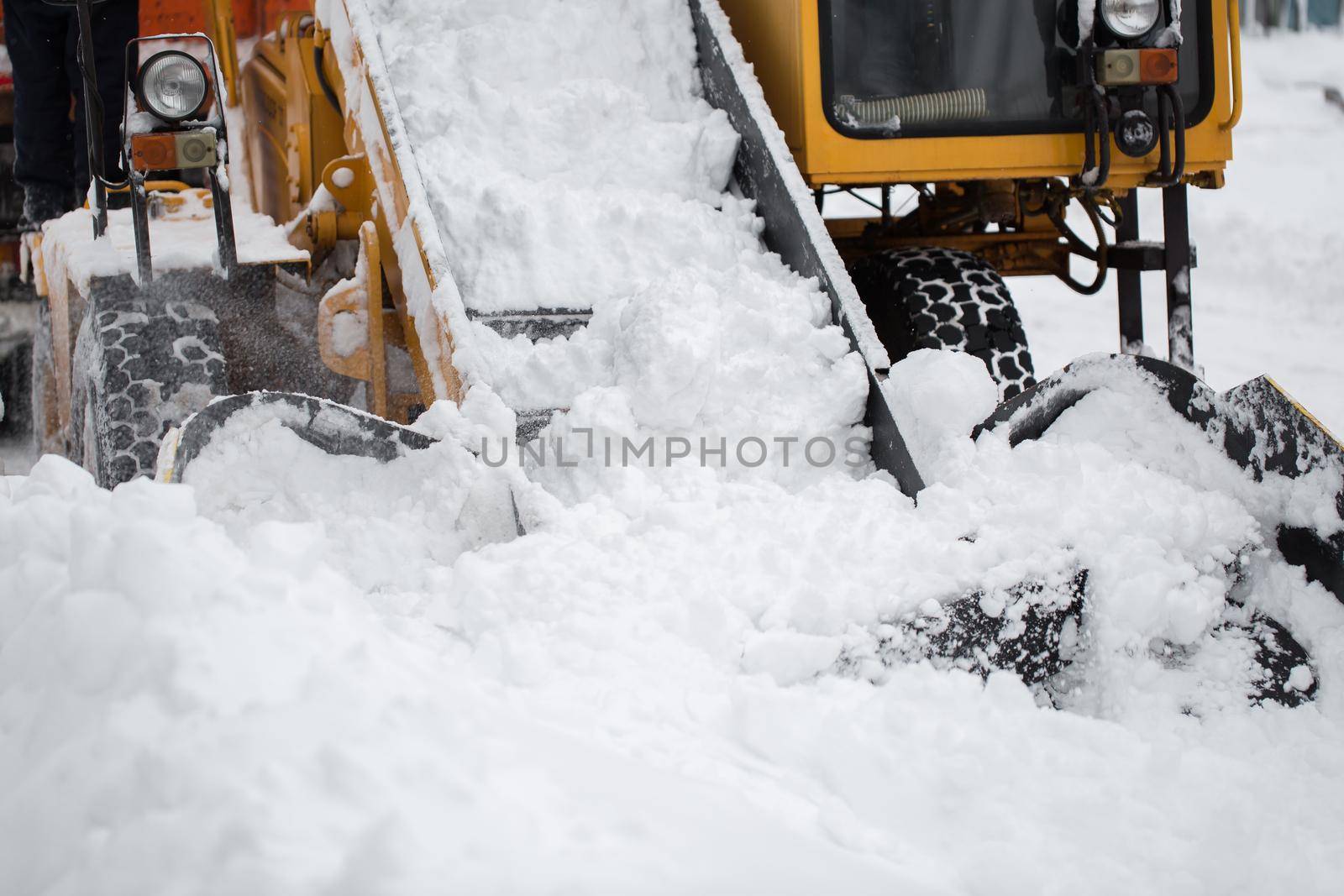 Paw snow loader with a conveyor belt in the winter on a city street