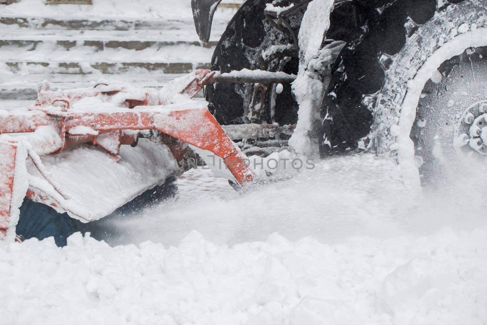 Rotating brush mounted on tractor to clean streets from snow closeup. Sweeping and cleaning sidewalk in winter. Tractor clean street from snow and ice from walkway after blizzard