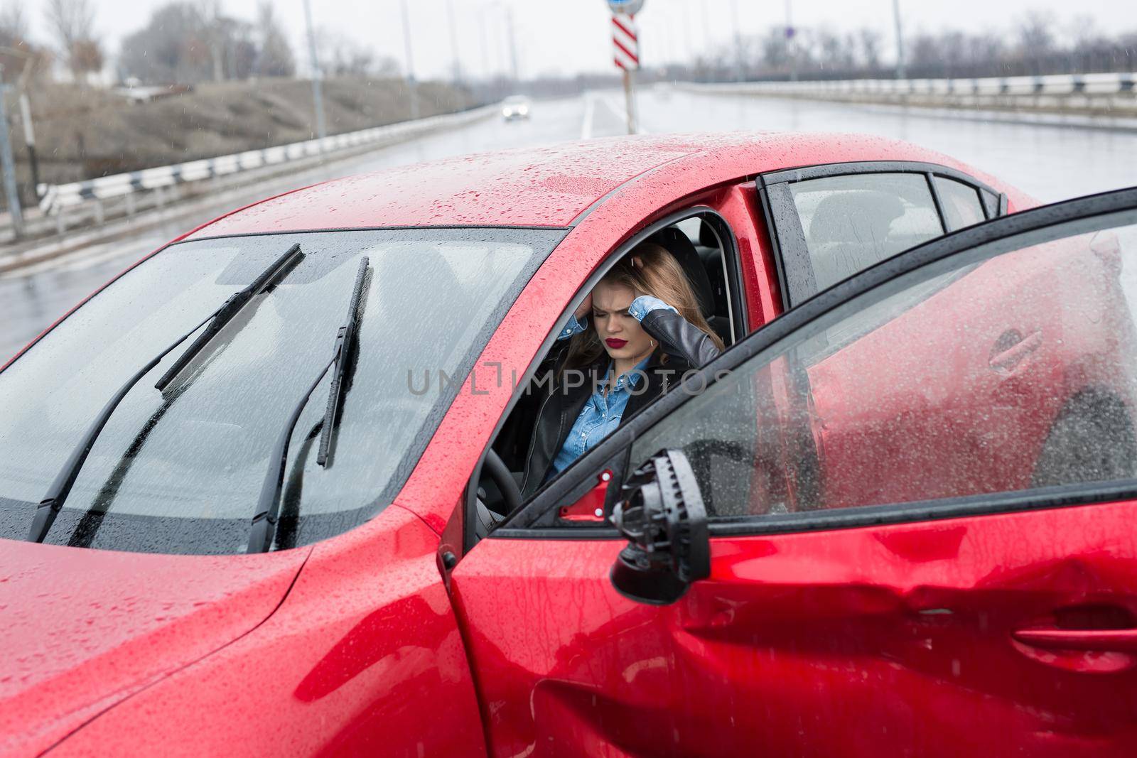 Young pretty scared woman in the car. Injured woman feeling bad after having a car crash. by StudioPeace