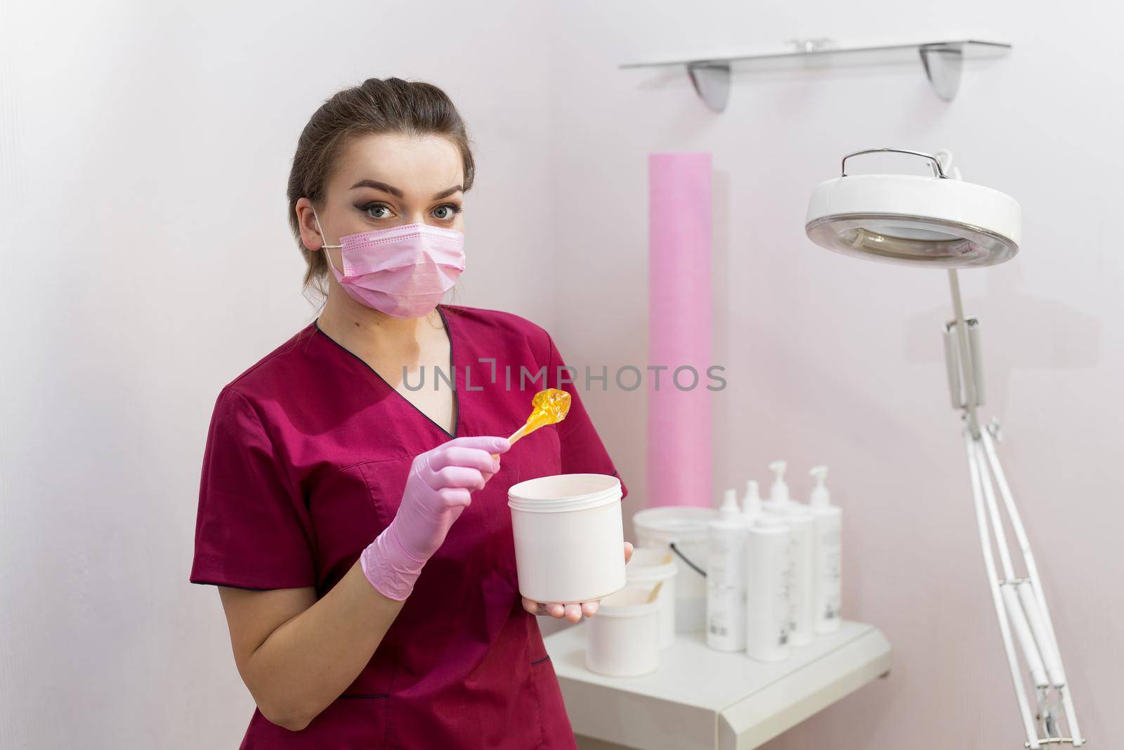 Portrait of a cosmetologist with sugar paste for depilation. Shugaring. Sugar paste out of the container with a spatula. Sugar paste for sugaring. Sugaring in beauty salon