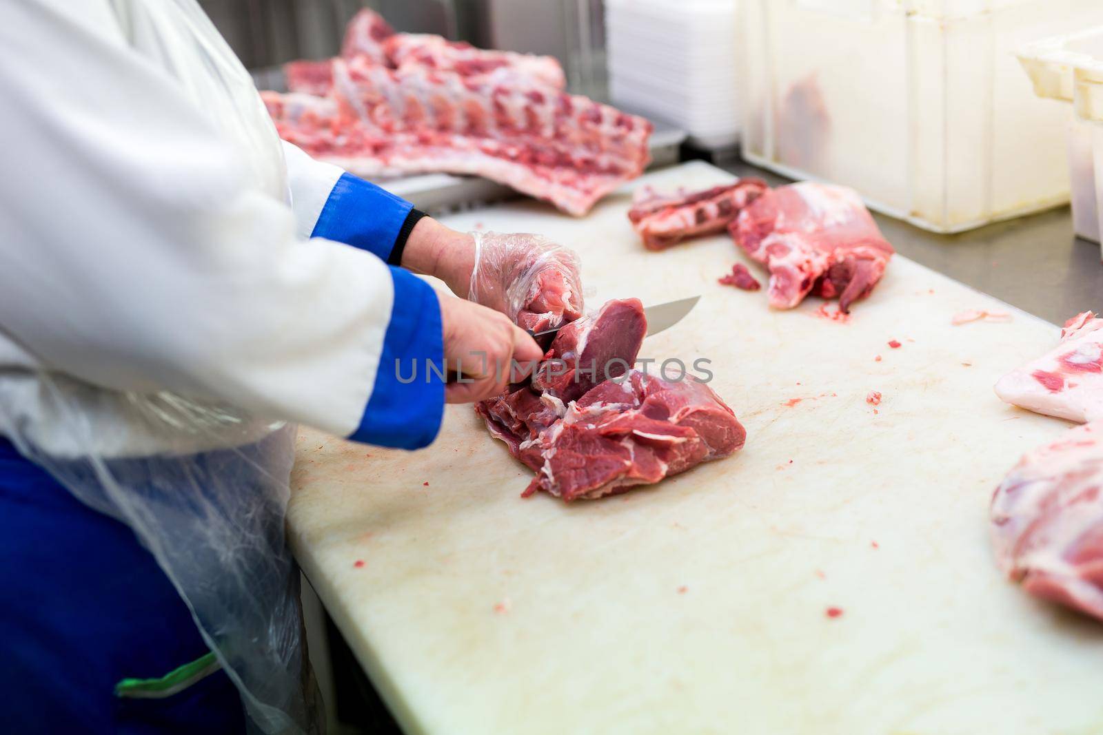 Closeup of the hands of a butcher cutting slices of raw meat off