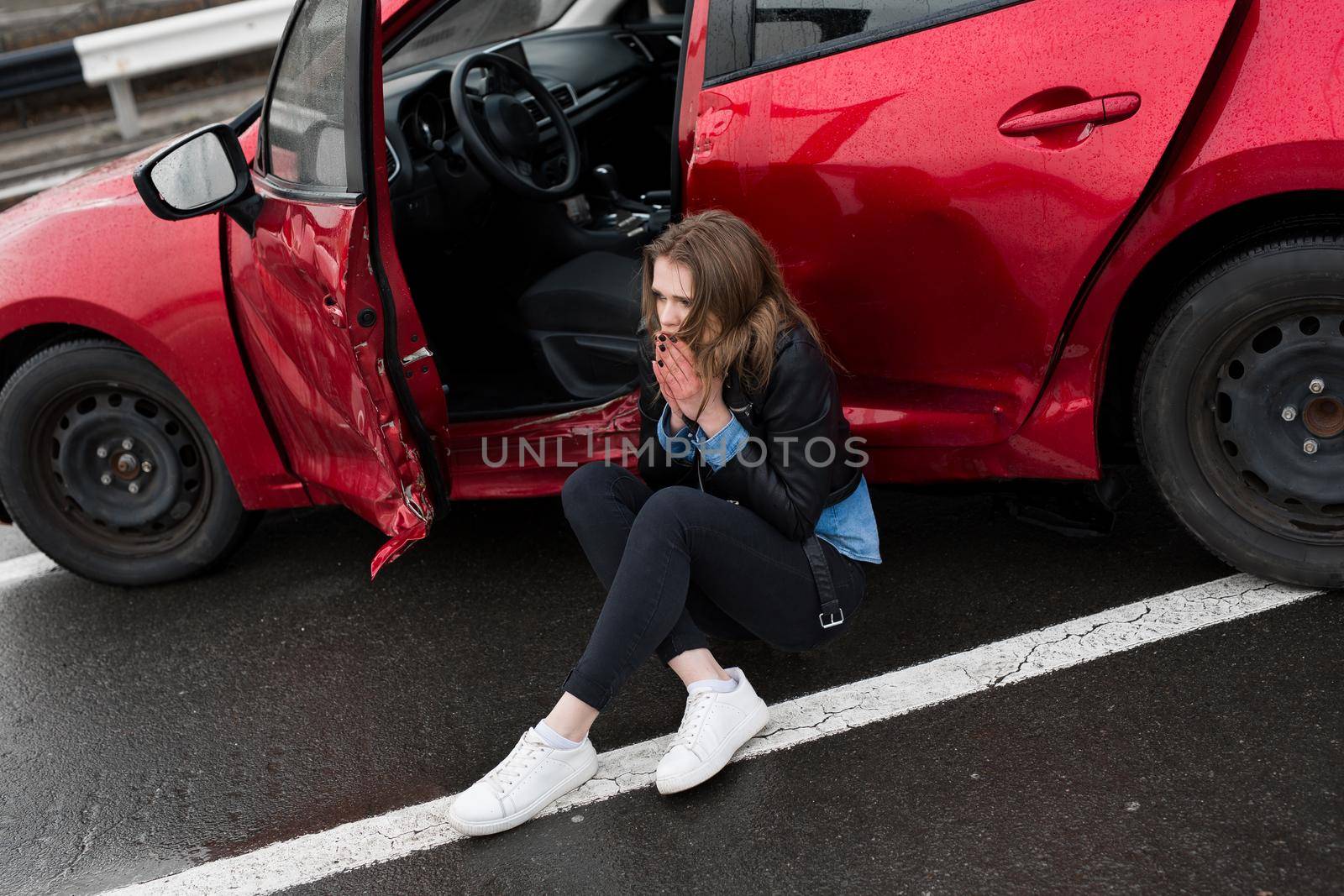 Woman sitting on the road after an accident. Injured woman feeling bad after having a car crash
