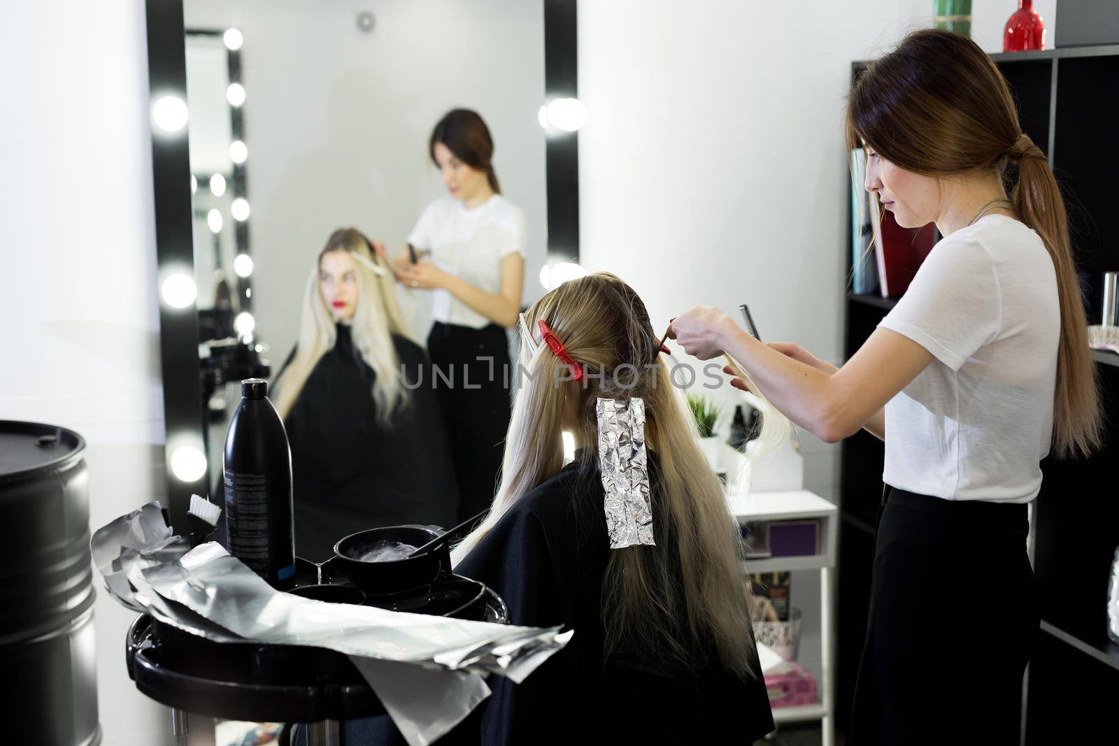 Blonde woman dying her hair at the beauty salon. by StudioPeace