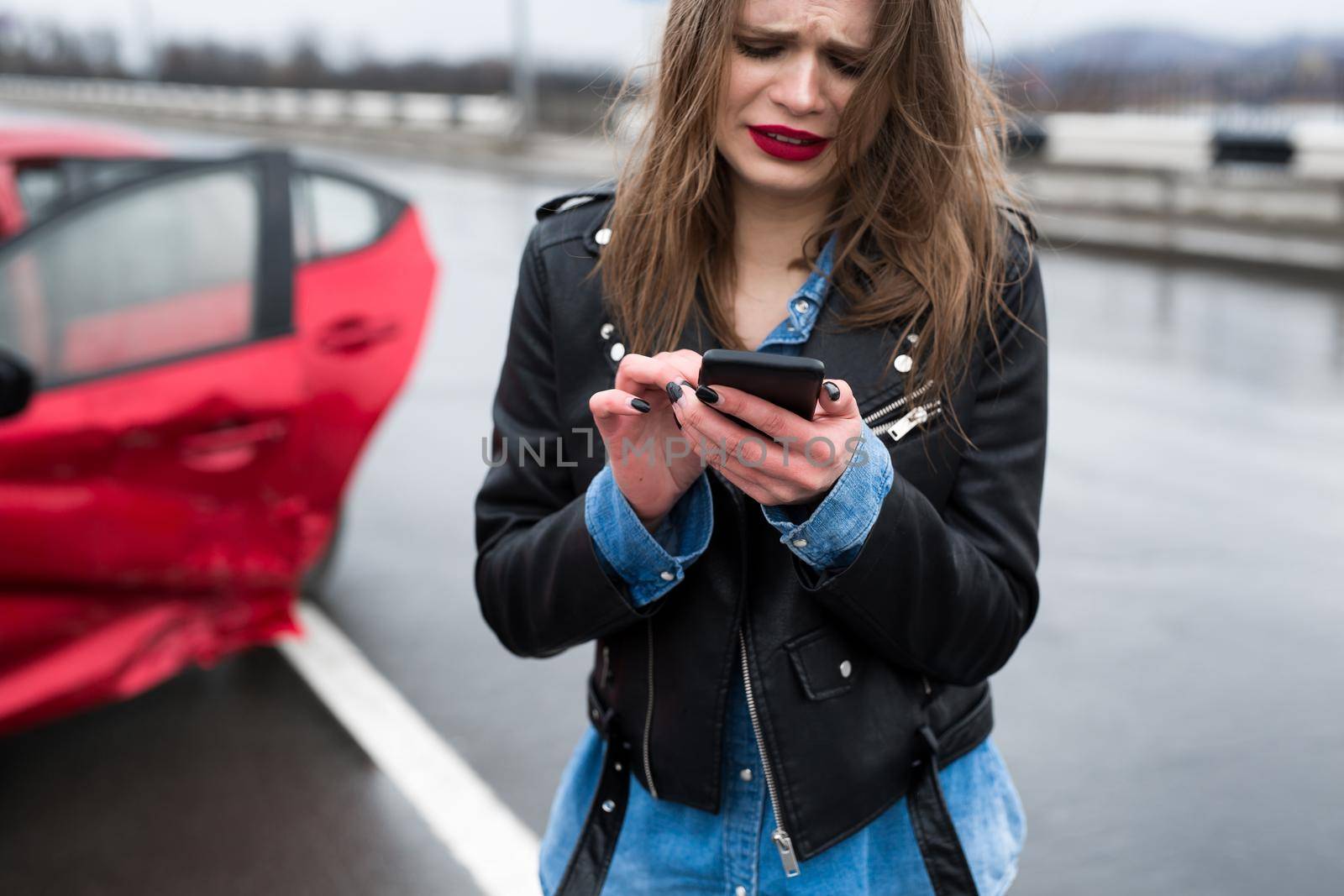 Woman calls to a service standing by a red car