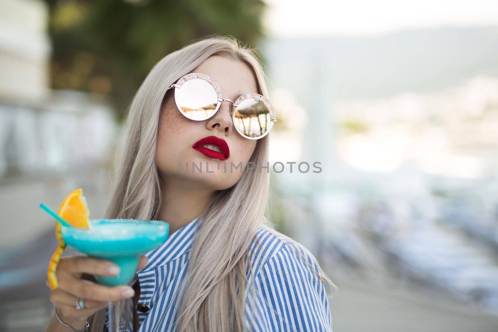 Portrait of a young woman with a cocktail glass at the bar. Beautiful girl enjoying alcoholic cocktail outside. by StudioPeace