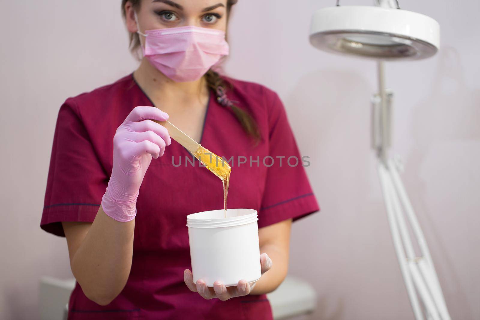 Cosmetician takes the sugar paste from the jar. Shugaring. Sugar paste out of the container with a spatula. Sugar paste for sugaring. Sugaring in beauty salon