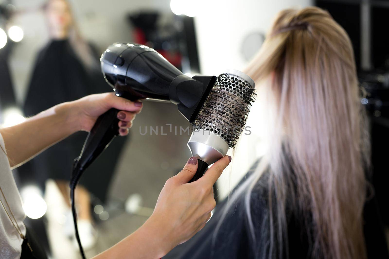 Drying long blonde hair with hair dryer and round brush. by StudioPeace