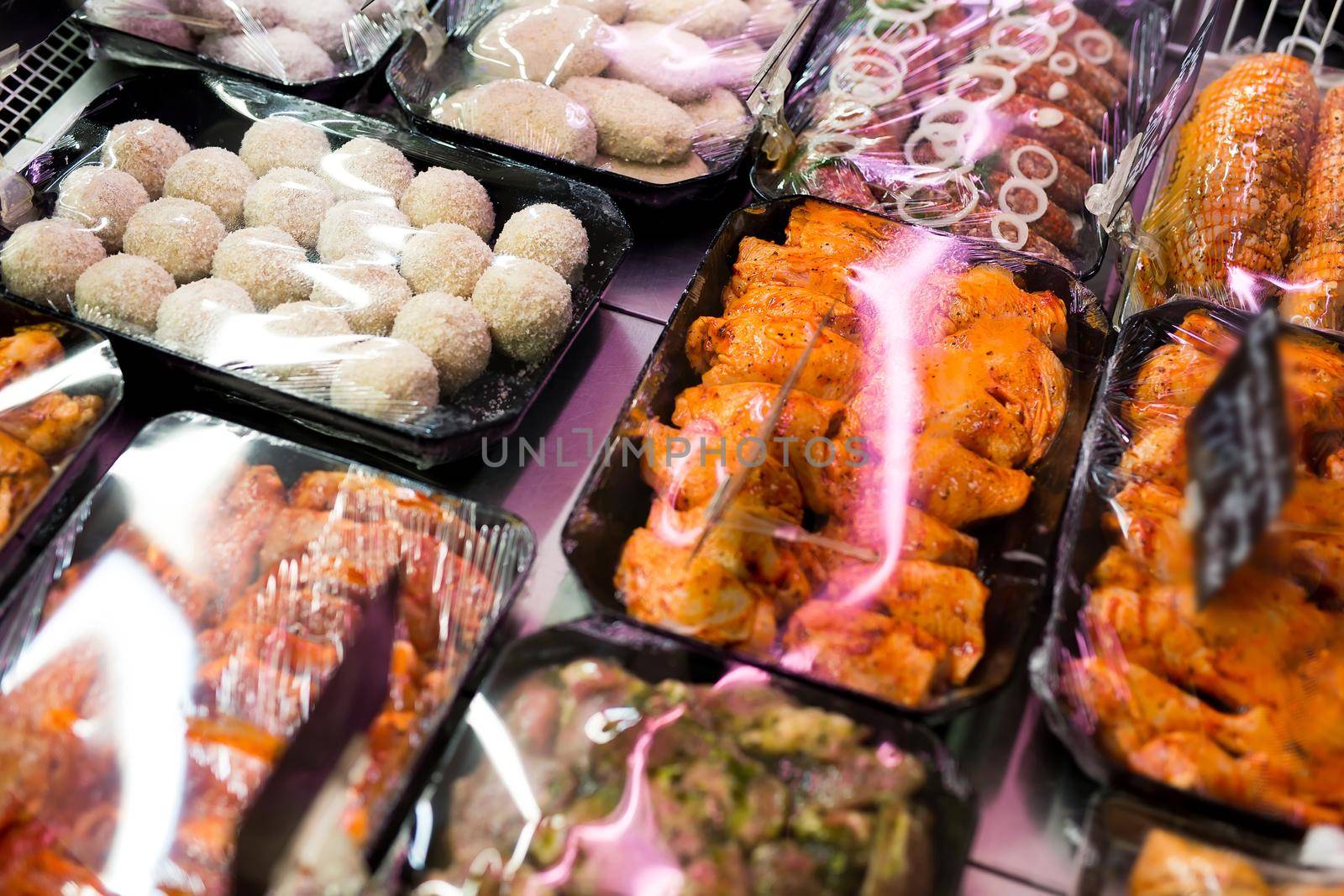 Meats in marinade on supermarket display, pre-cooked food