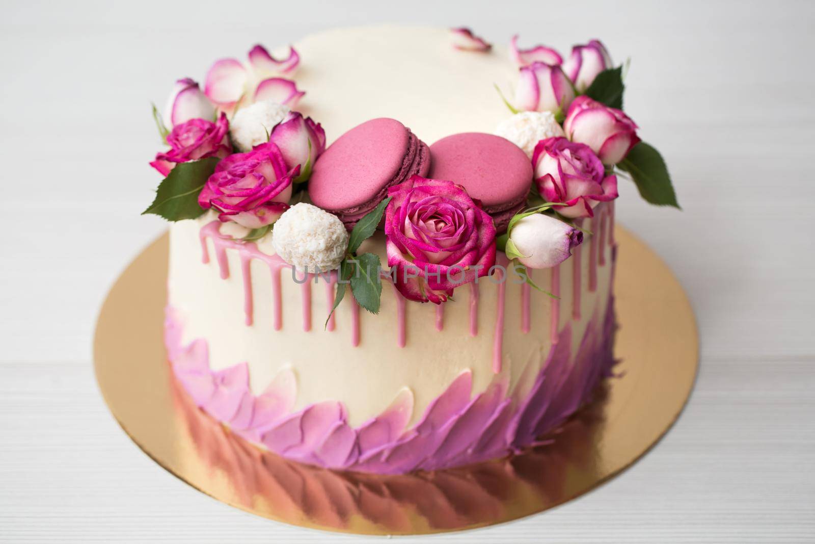 Cake with roses, sweets and lilac macaroons.