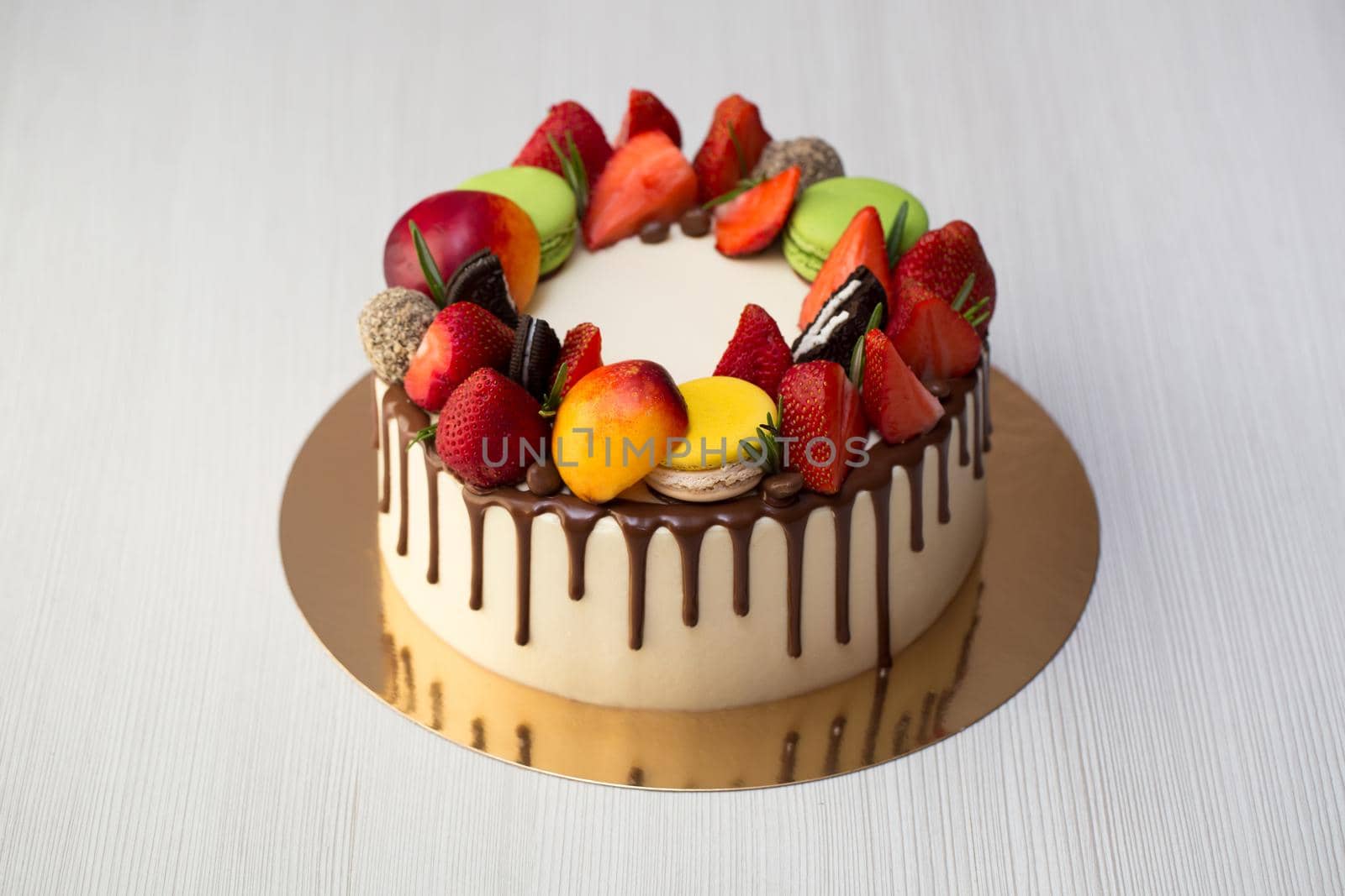 Cake with chocolate drips, strawberries, peaches macaroons rosemary