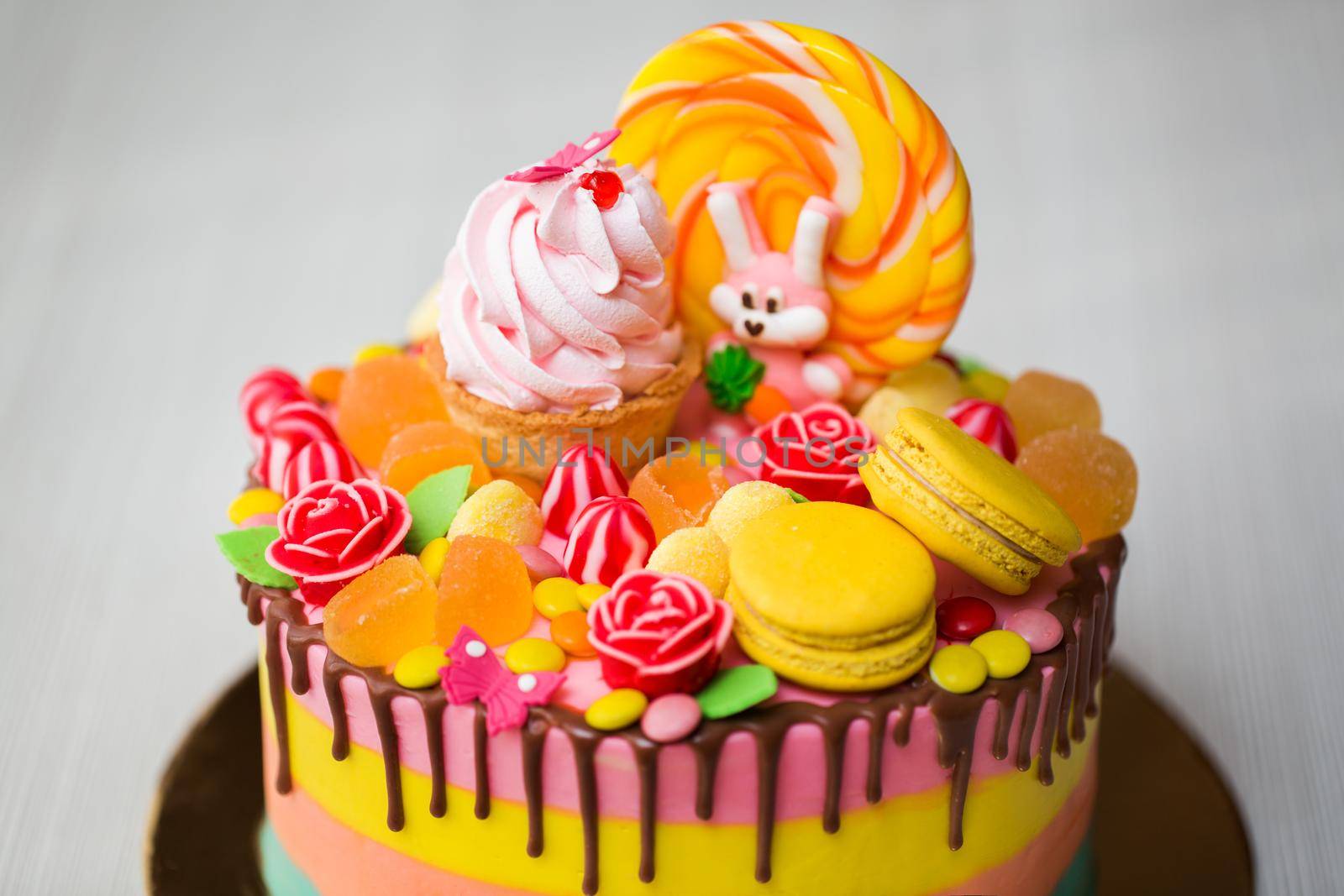 Colourful cake for a kid's birthday party with Lollipop, candy, marmalade, cupcakes and Bunny