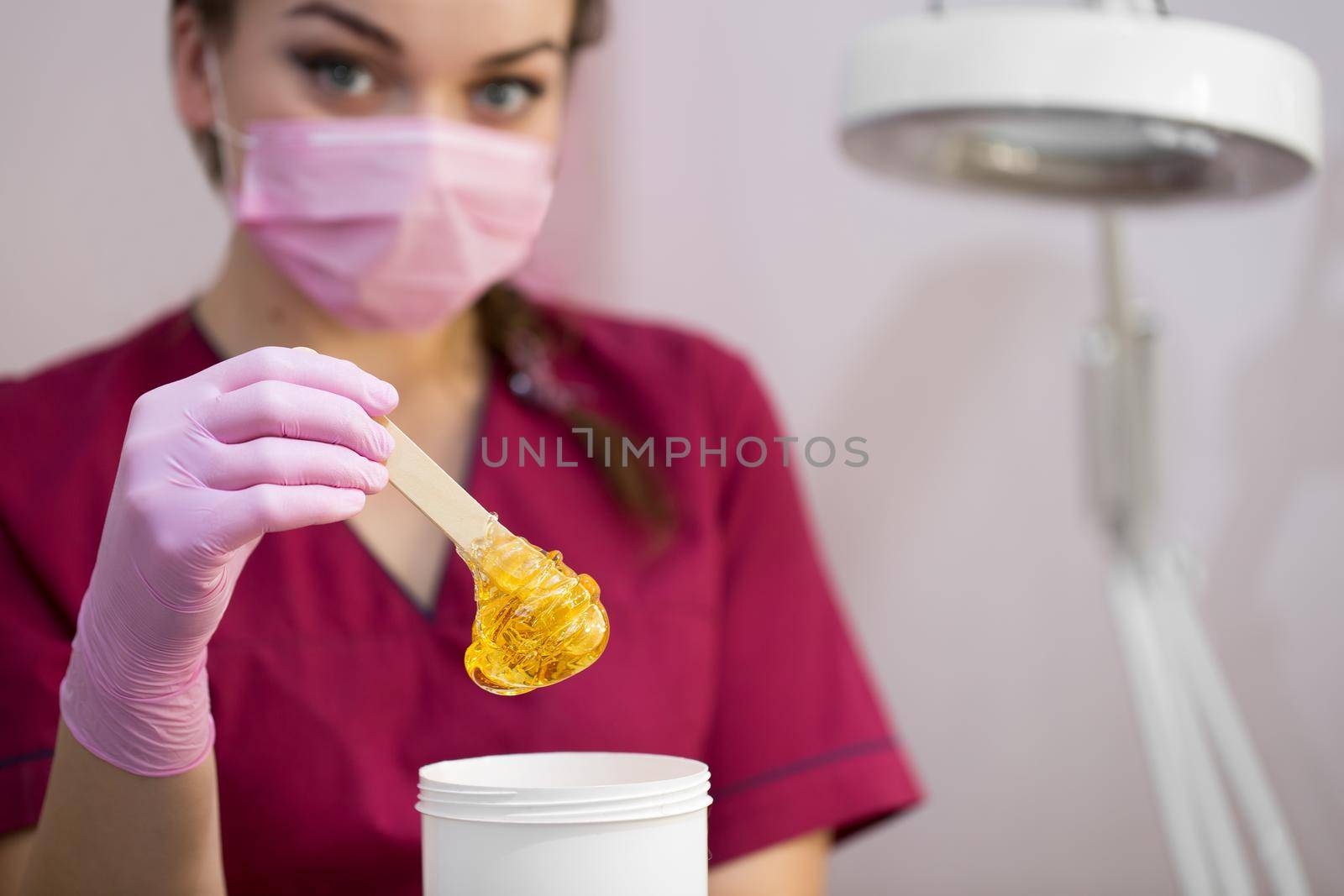 Cosmetician takes the sugar paste from the jar. Shugaring. Sugar paste out of the container with a spatula. Sugar paste for sugaring. Sugaring in beauty salon