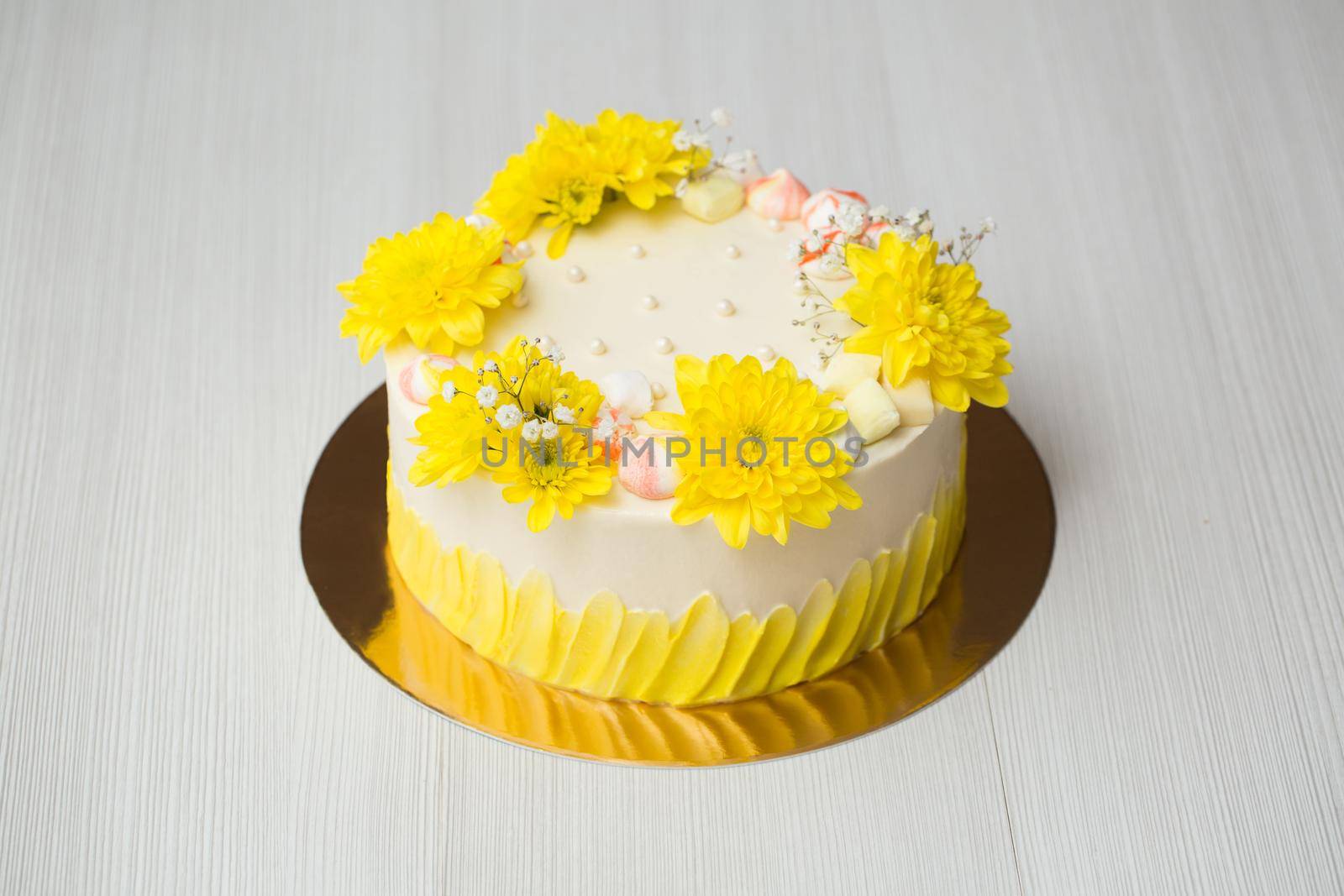 Cake with yellow stains, yellow chrysanthemums and meringue