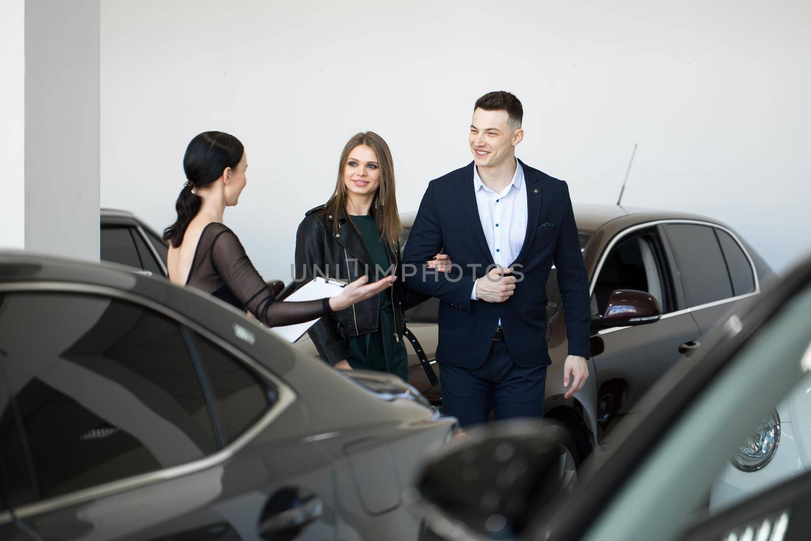 Auto business, car sales - a happy couple with a car dealer in a car dealership or salon