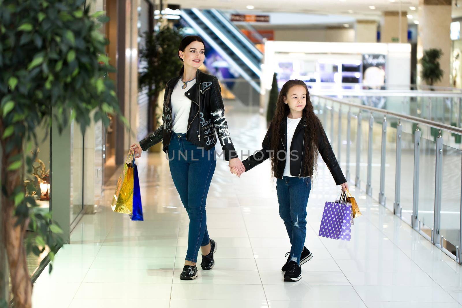 Beautiful sisters are holding shopping bags and smiling while doing shopping in mall. by StudioPeace
