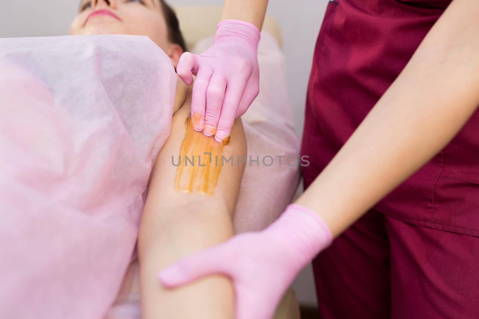 Close-up of a shugaring master applying thick sugar paste on a young girl's hand, removing unwanted hair. Hair removal with a special sugar paste has many advantages over wax depilation. by StudioPeace