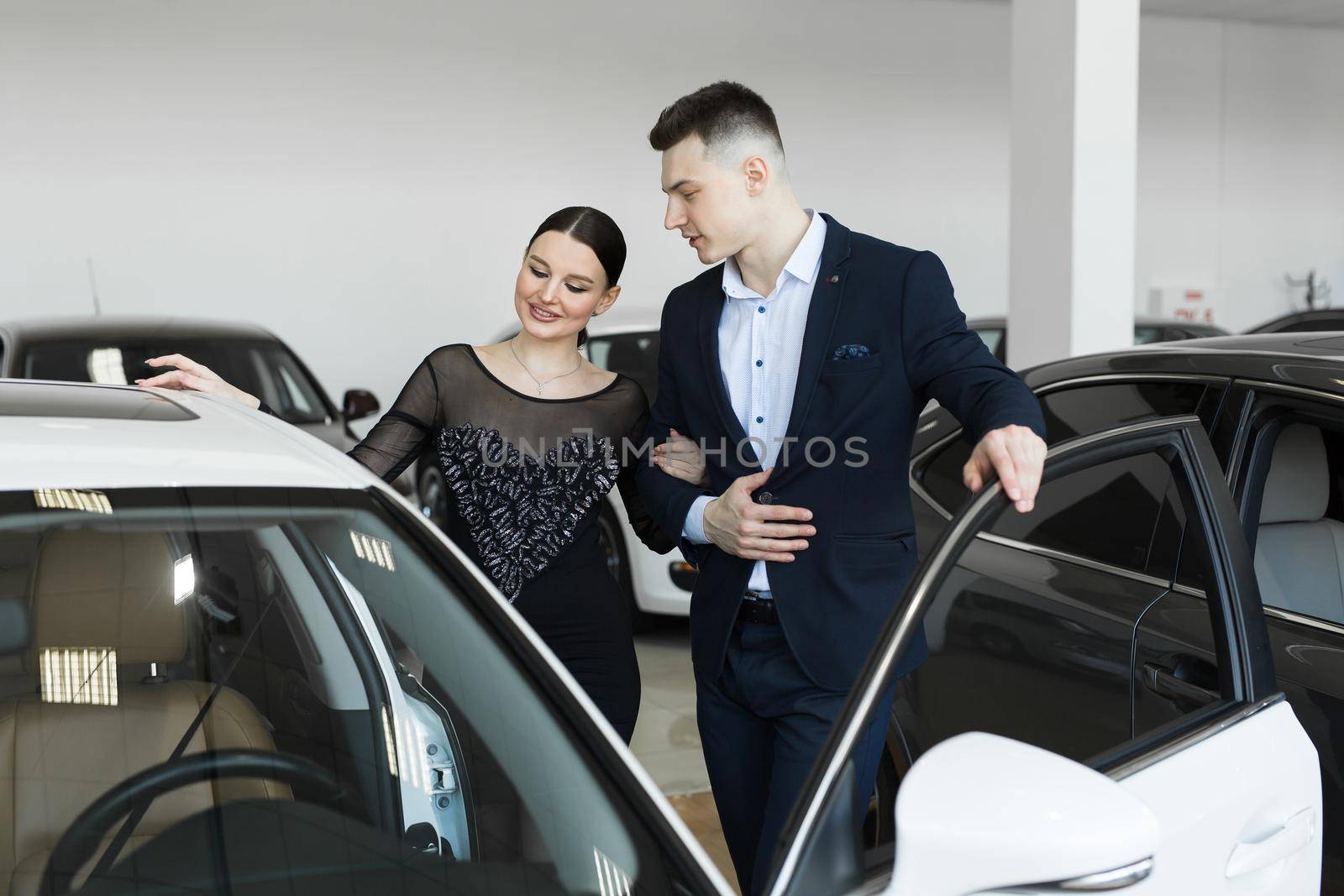 A couple husband and wife choose a car to buy at a car dealership. by StudioPeace